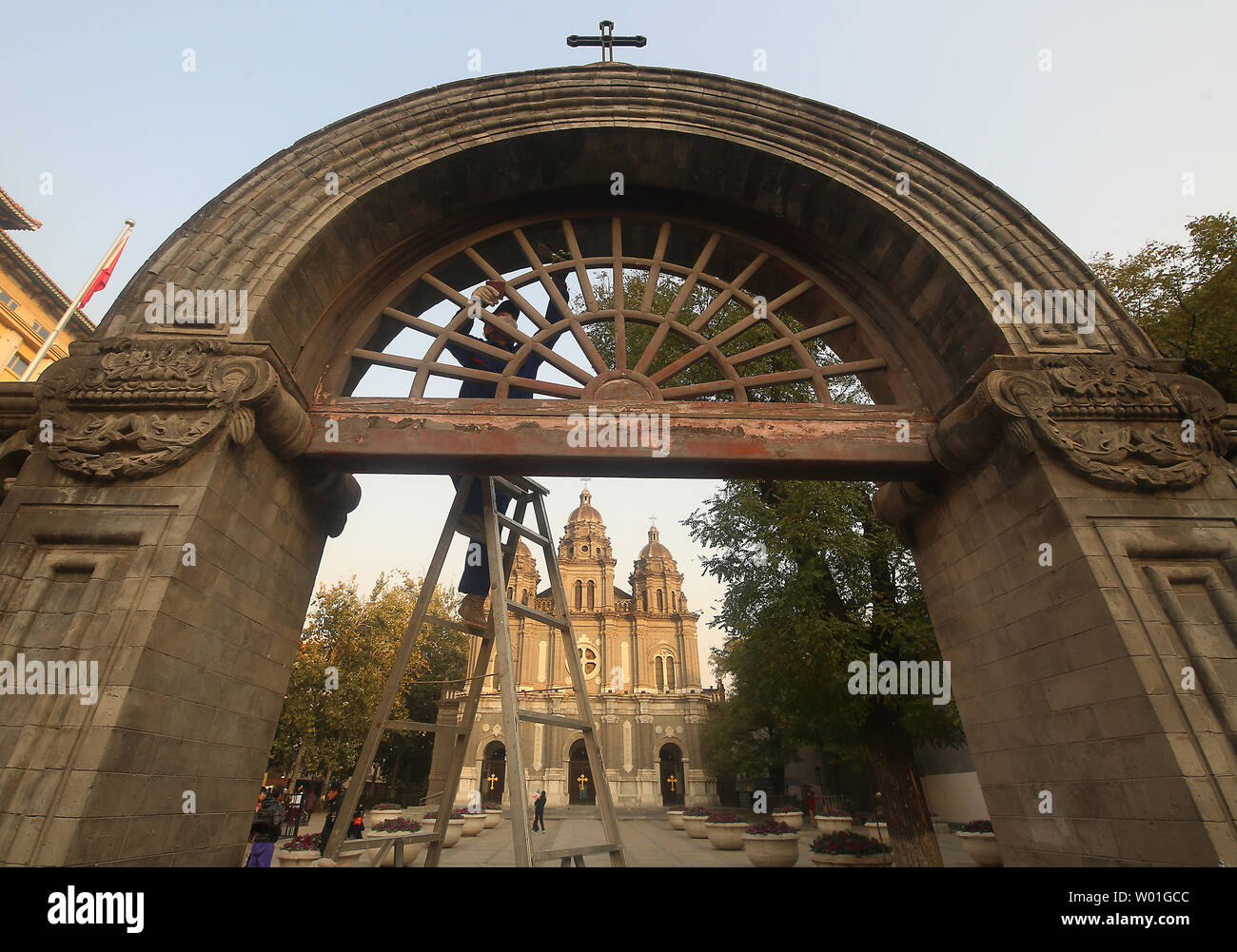 A Chinese worker climbs a ladder to peel off old paint on a gate in front of St. Joseph's Church, one of the oldest Catholic churches still open, in central Beijing on November 19, 2018.  The church has been destroyed twice in the past due to prior governments' anti-Western sentiments and policies, but was opened recently for religious services.     Photo by Stephen Shaver/UPI Stock Photo