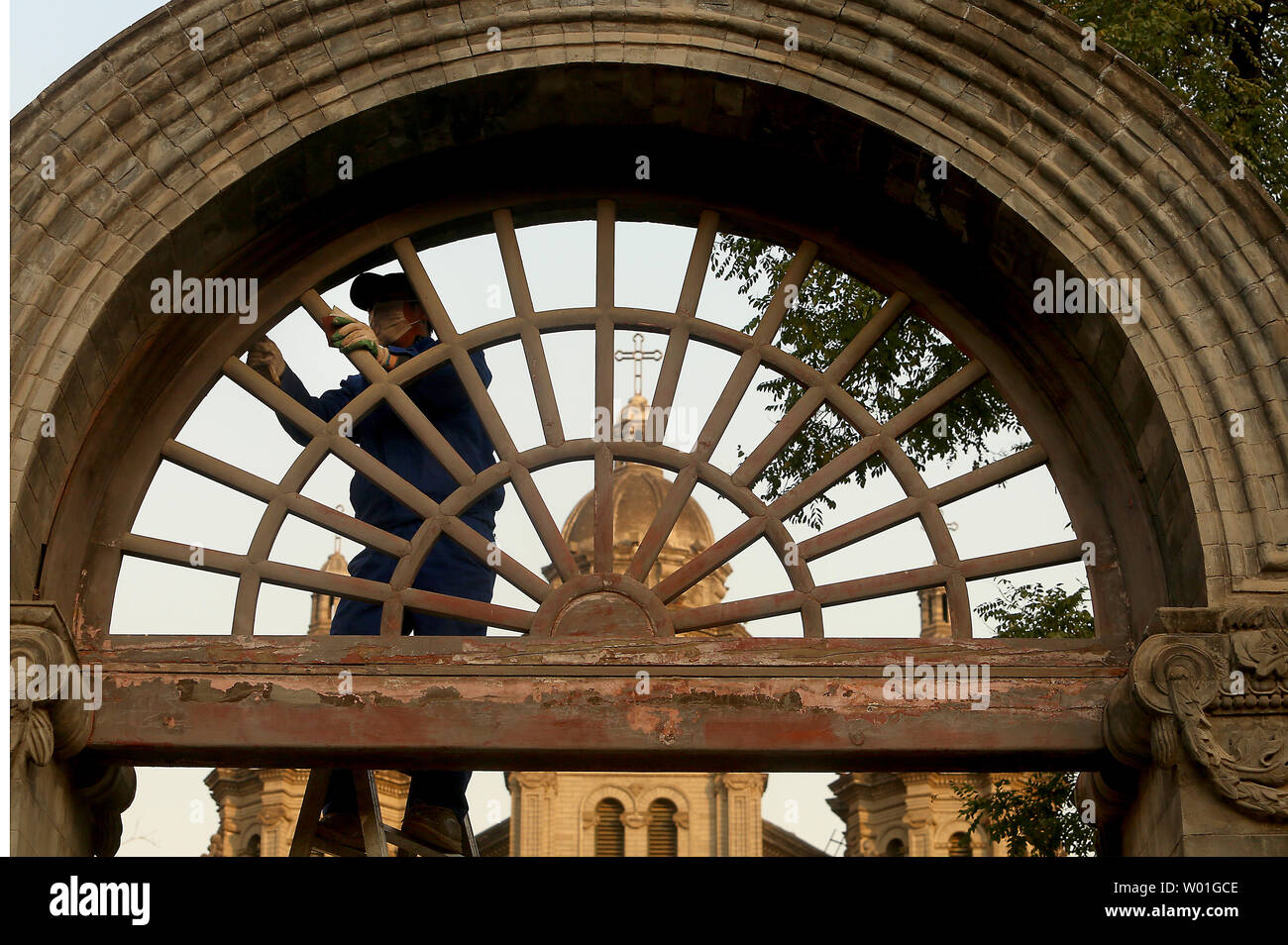 A Chinese worker climbs a ladder to peel off old paint on a gate in front of St. Joseph's Church, one of the oldest Catholic churches still open, in central Beijing on November 19, 2018.  The church has been destroyed twice in the past due to prior governments' anti-Western sentiments and policies, but was opened recently for religious services.     Photo by Stephen Shaver/UPI Stock Photo