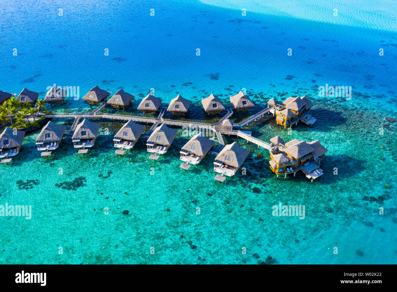 Travel vacation paradise aerial drone video with overwater bungalows in coral reef lagoon sea