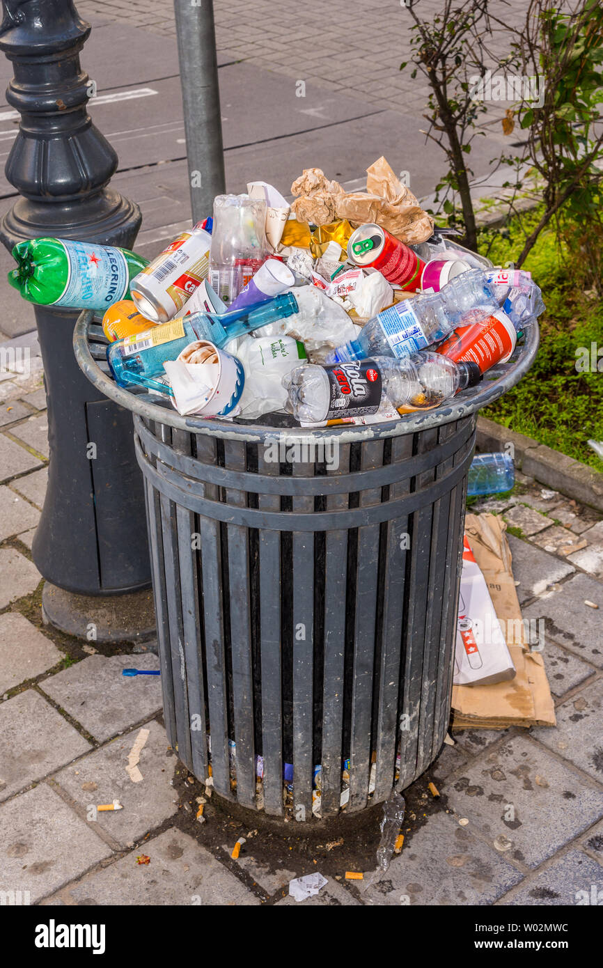 Public waste basket overflowing with discarded soft drinks bottles and cans - Brussels, Belgium. Stock Photo