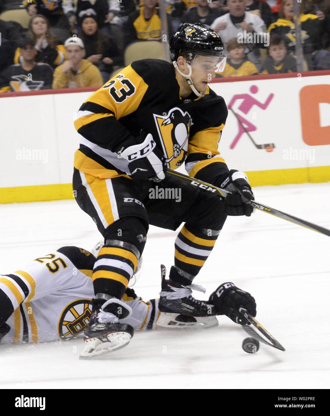 Boston Bruins defenseman Brandon Carlo (25) knocks the puck away from Pittsburgh Penguins center Teddy Blueger (53) but  receives a tripping penalty during the second period of the Pens 4-2 win at PPG Paints Arena in Pittsburgh on March 10, 2018.   Photo by Archie Carpenter/UPI Stock Photo