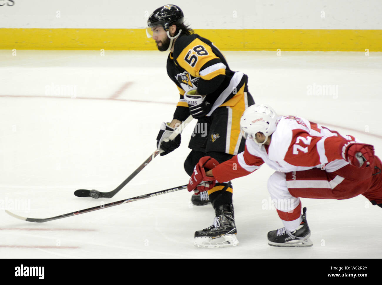 Detroit Red Wings center Andreas Athanasiou (72) reaches for the puck as Pittsburgh Penguins defenseman Kris Letang (58) takes a shot during the second period of the 4-1 win against the Detroit Red Wings at PPG Paints Arena in Pittsburgh on April 4, 2019.   Photo by Archie Carpenter/UPI Stock Photo