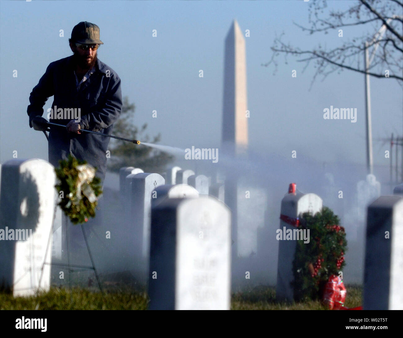 A maintenance worker cleans headstones at Arlington National Cemetery, in Arlington, Virginia on December 20, 2006.  Since 1864, when the first coffin was interred, more than 200,000 burials have taken place in the more than 600 acres of land devoted to America's honored dead.   (UPI Photo/Kevin Dietsch) Stock Photo