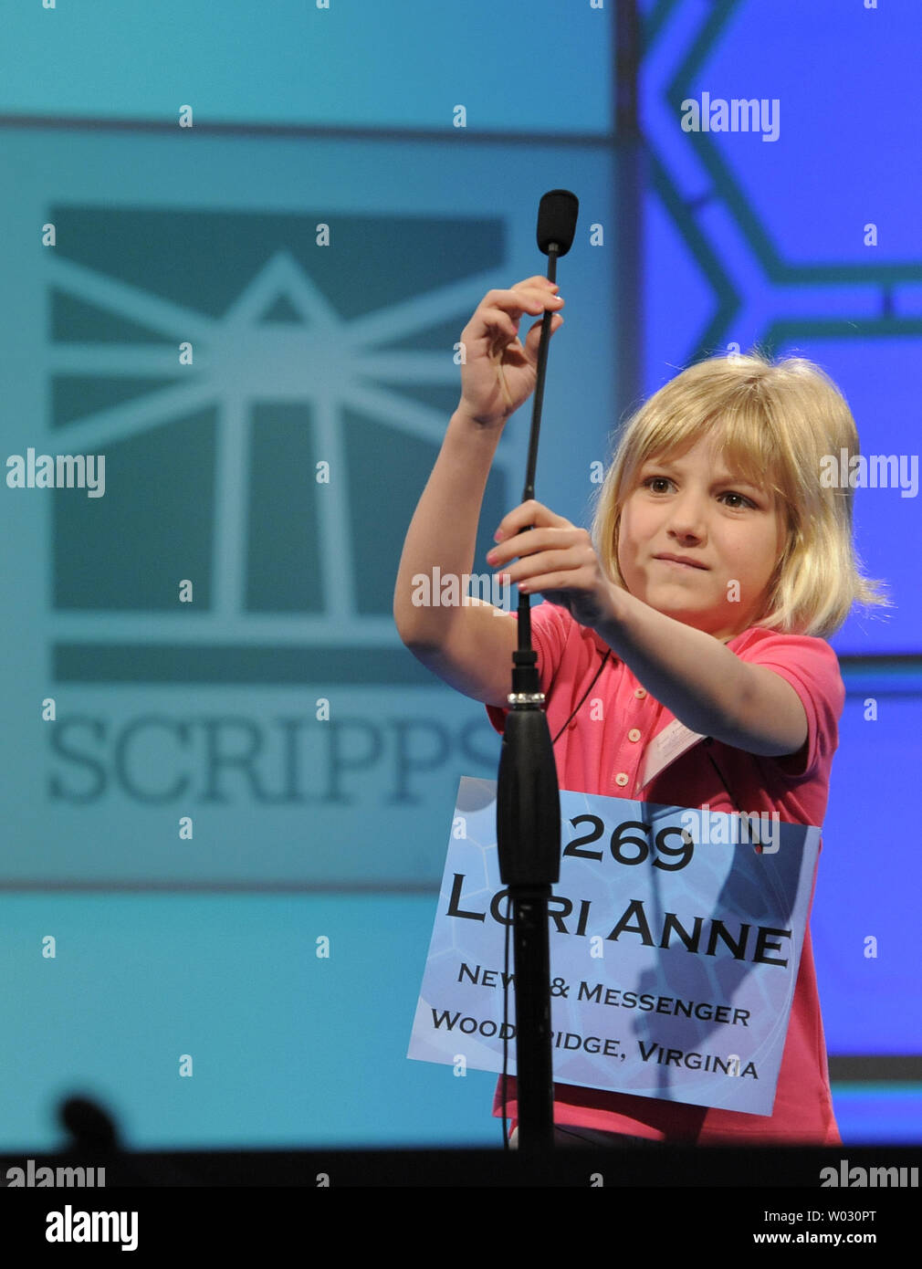 Lori Anne Madison, 6, of Woodbridge, Virginia, adjusts the microphone as he steps up to accept her first word, during opening round of the Scripps National Spelling Bee, May 30, 2012, in National Harbor, Maryland. Madison, the youngest known qualifier in the history of the contest, correctly spelled the word 'dirigible', a lighter-than-air aircraft, to advance.        UPI/Mike Theiler Stock Photo