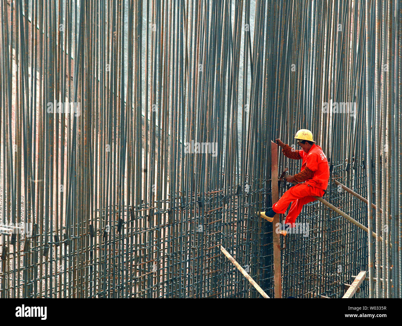 A construction worker ties steel rebars together on a development project in Shenzhen, a major city in Southern China's Guangdong Province on October 22, 2013.  China has initiated a smart city program countrywide as a part of its efforts to explore ways to foster a new type of urbanization.    UPI/Stephen Shaver Stock Photo