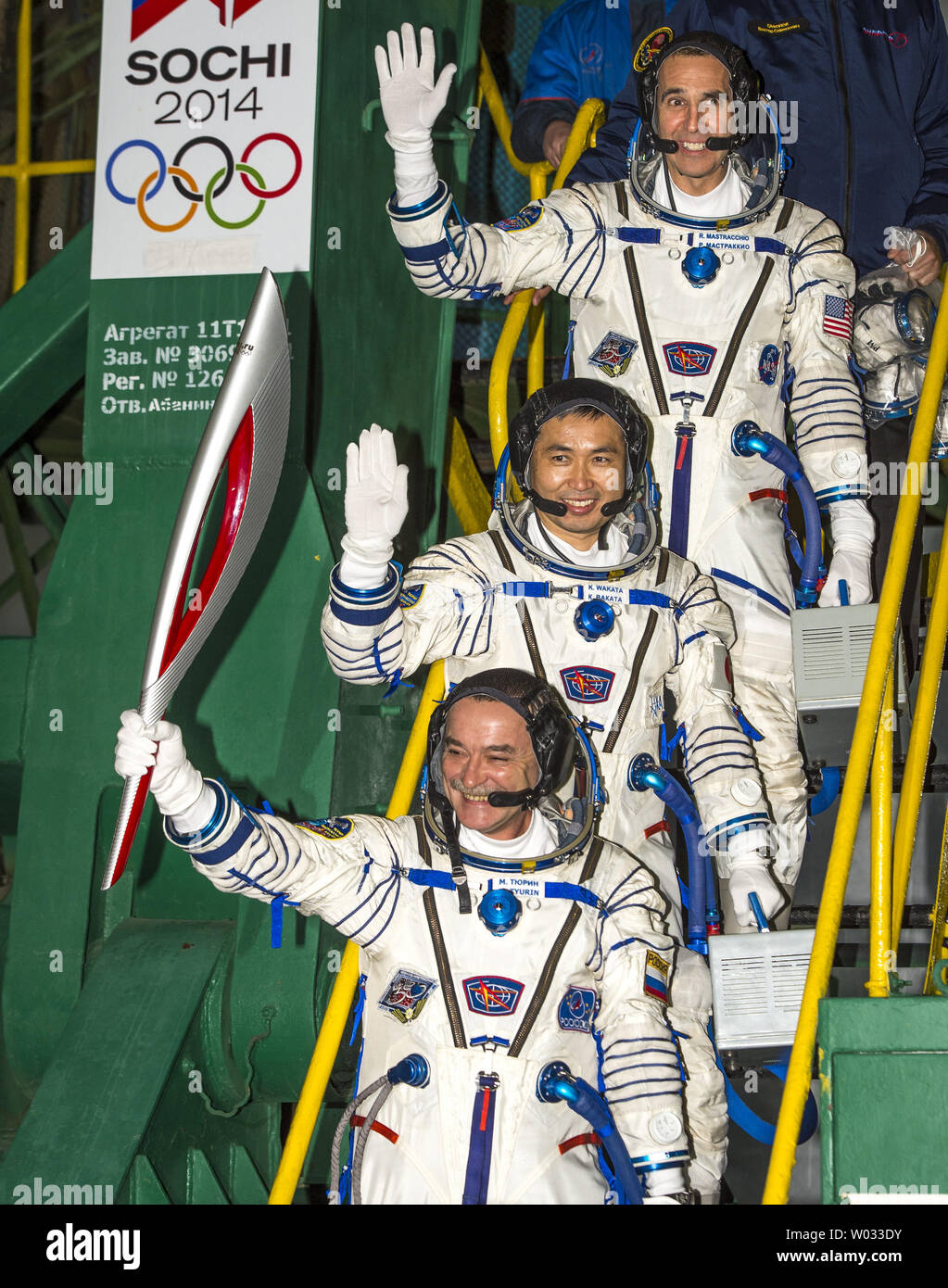 Expedition 38 Soyuz Commander Mikhail Tyurin of Roscosmos, holding the Olympic torch, Flight Engineer Koichi Wakata of the Japan Aerospace Exploration Agency, and, Flight Engineer Rick Mastracchio of NASA top, wave farewell prior to boarding the Soyuz TMA-11M rocket for launch at the Baikonur Cosmodrome in Kazakhstan, November 7, 2013.  The Olympic torch will have a four-day visit to the International Space Station.  Tyurin, Mastracchio, and, Wakata will spend the next six months aboard the International Space Station. UPI/Bill Ingles/NASA Stock Photo