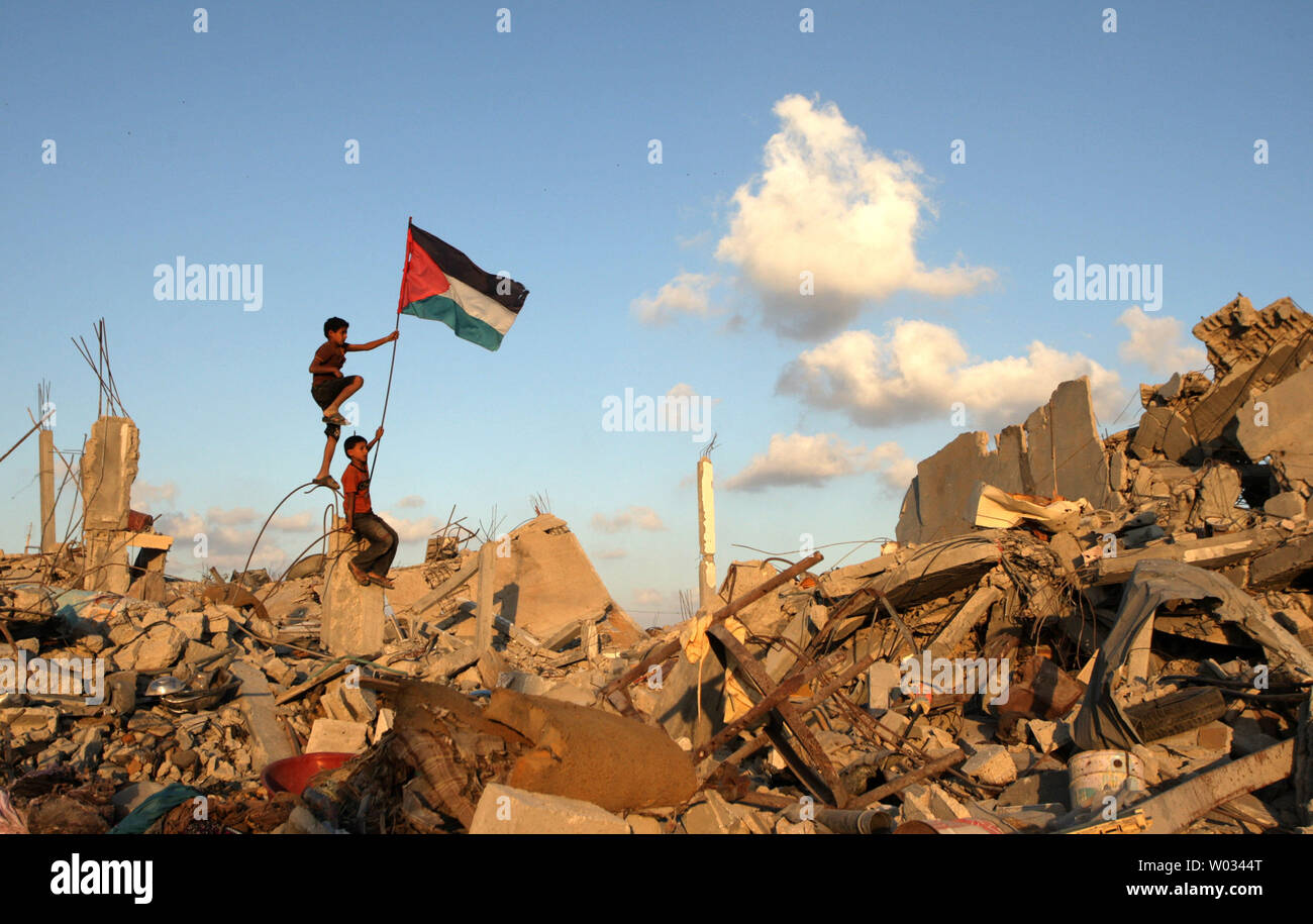 Palestinian children hold aloft their national flag amidst the rubble of buildings in the Khuzaa neighborhood of Khan Yunis on October 1, 2014. The destruction was the result of a seven-week long conflict between the Israeli army and Hamas militants in the Gaza Strip. UPI/Ismael Mohamad Stock Photo