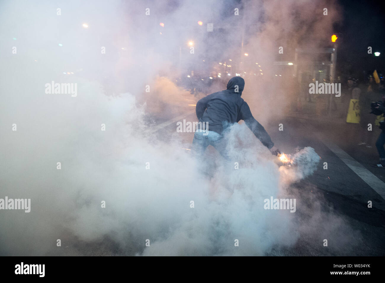 A protestor picks up a smoke canister and throws it back at the police at Pennsylvania Ave and North Ave in Baltimore as the 10pm curfew grew closer in Baltimore, Maryland on April 28, 2015.  Protests have erupted after death of Freddie Gray. Photo Ken Cedeno/UPI. Stock Photo