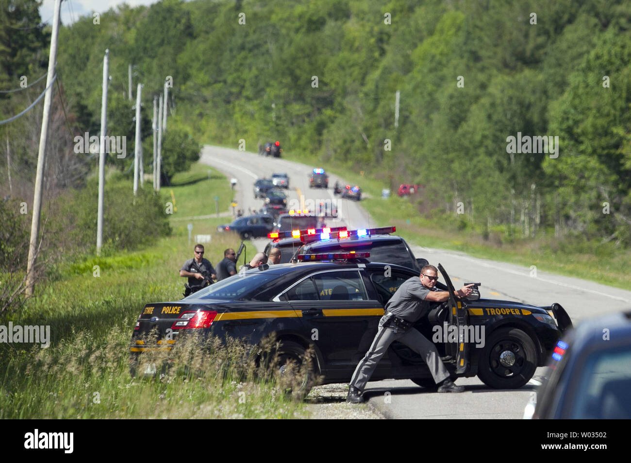 Law enforcement personnel take cover after cornering two escaped prisoners off of Route 30 in Malone, New York on June 26, 2015.  At least one prisoner, Richard Matt, is believed to have been shot dead by law enforcement and second prisoner, David Sweat, may still be on the loose. Photo by Matthew Healey/UPI Stock Photo