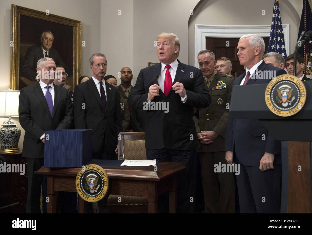 President Donald Trump adjusts his jacket after signing H.R. 2810, the National Defense Authorization Act for Fiscal Year 2018, during a signing ceremony in the Roosevelt Room on December 12, 2017, in Washington, D.C. Trump was joined by, from left to right, Defense Secretary Jim Mattis, Chairman of the House Armed Services Committee Mac Thornberry, R-TX, Chairman of the Joint Chiefs of Staff Joseph F. Dunford, Vice President Mike Pence and members of the military. Photo by Kevin Dietsch/UPI Stock Photo