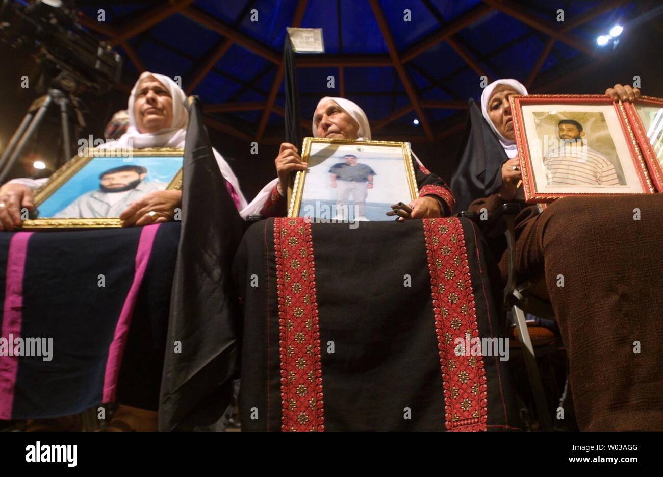 Palestinian women hold pictures of loved ones being held in Israeli jails as they sit at the front of a gathering of groups opposed to the Geneva Accord in Gaza City, Monday, Dec. 1, 2003. A symbolic Middle East peace plan dubbed 'the Geneva Accord' is due to be launched in a ceremony in Switzerland on Monday. By laying out steps to overcome longstanding obstacles to a 'two-state solution' in the Israeli-Palestinian conflict, the document goes beyond a U.S.-backed 'road map.'   (UPI photo/ Ismael Mohamad ) Stock Photo