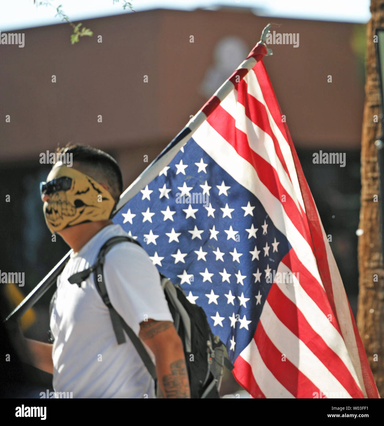 A man walks through the crowd of demonstrators carrying an American Flag, which is hung upside down, in reaction to the US Supreme Court's decision on Arizona's controversial SB1070 immigration law across Central Avenue from the Immigration and Customs Enforcement offices in Phoenix, Arizona, June 25, 2012.  UPI/Art Foxall Stock Photo