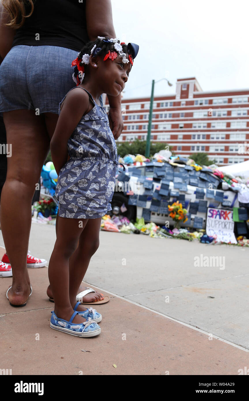 A young girl stands by a memorial outside police headquarters on Lamar Streer on July 9, 2016 in Dallas Texas. Days after a lone sniper opened fire on a peaceful 'Black Lives Matter' march killing five Dallas policemen.         Photo By Chris McGathey Stock Photo