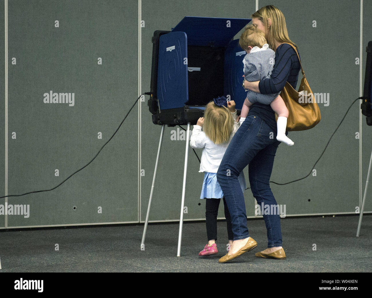 A woman juggles two children as she votes in the South Carolina primary election, in Daniel Island, South Carolina on February 20, 2016. Photo by Kevin Dietsch/UPI Stock Photo