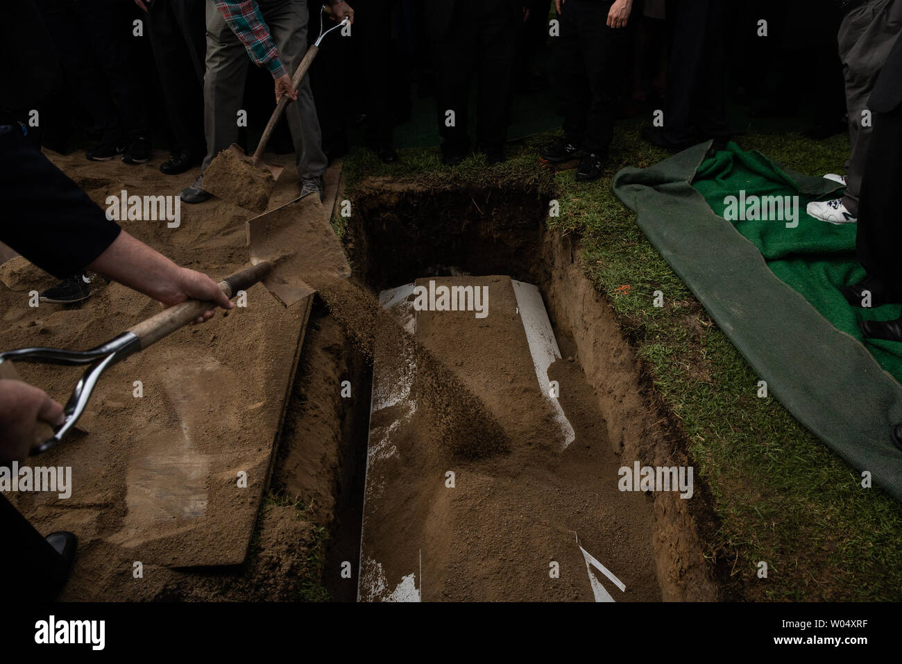Mourners shovel dirt over the coffin during the burial service for Lori