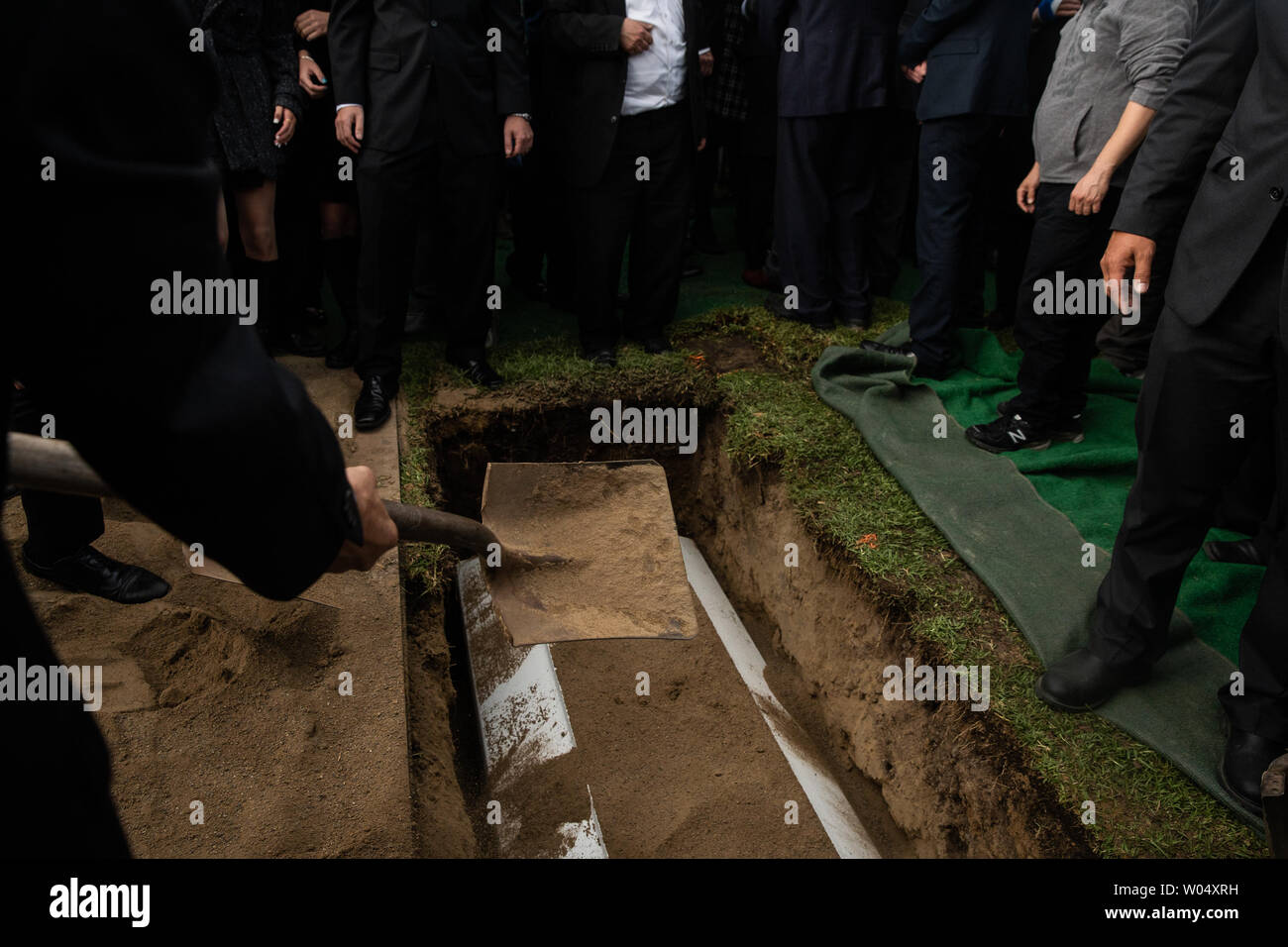 Mourners shovel dirt over the coffin during the burial service for Lori