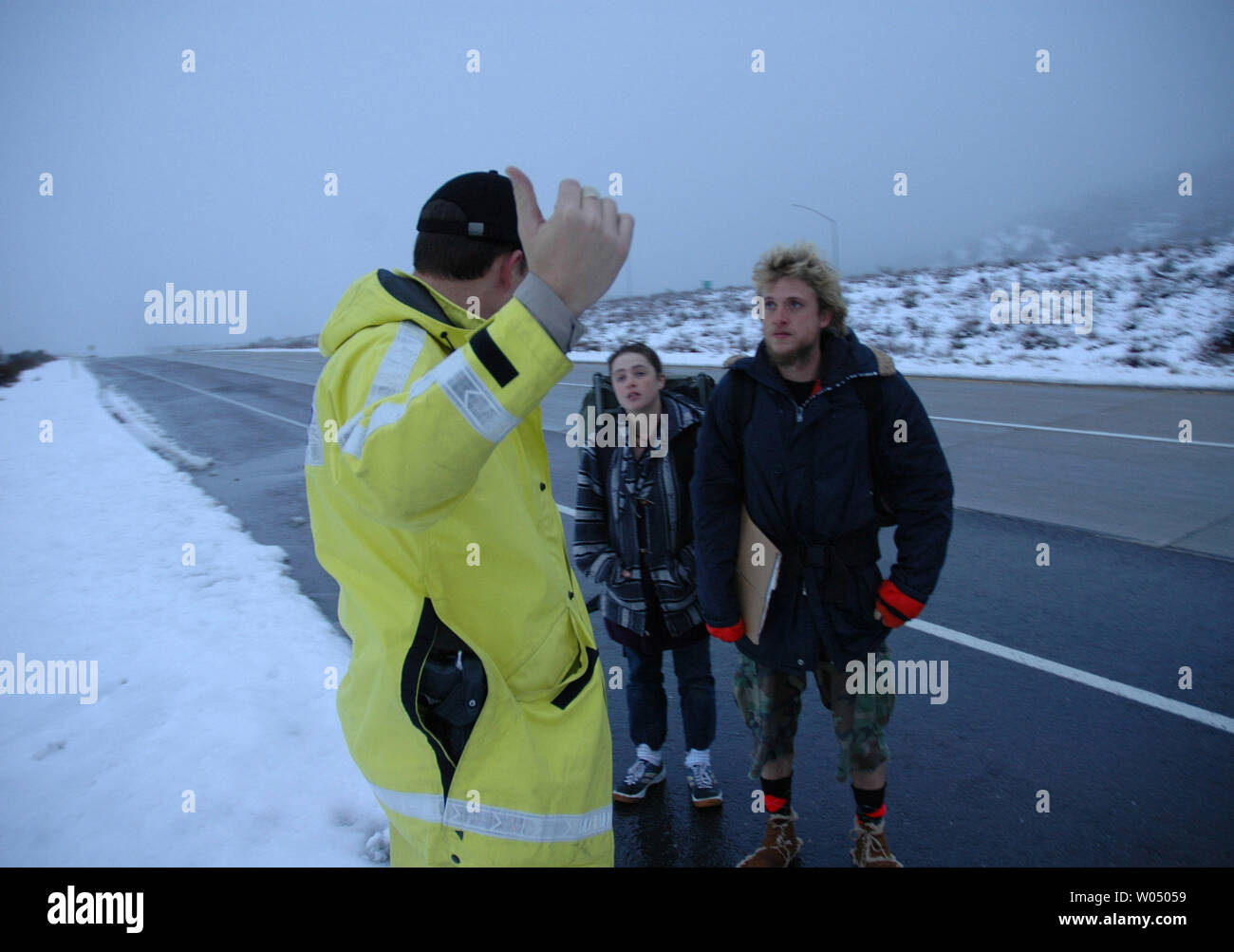 CHP officer M. Miller talks to Chad Nevins from Montana (right) and Lisa Kaleper (middle) of Wisconsin about illegal hitch hiking on Interstate 8 before giving them a ride to the nearby  town of Pine Valley, as yet another winter storm left a coating of snow in the San Diego mountains as low as 3,000 feet and flooding in low laying areas on January 4, 2005.                                                           (UPI Photo/ Earl S. Cryer) Stock Photo