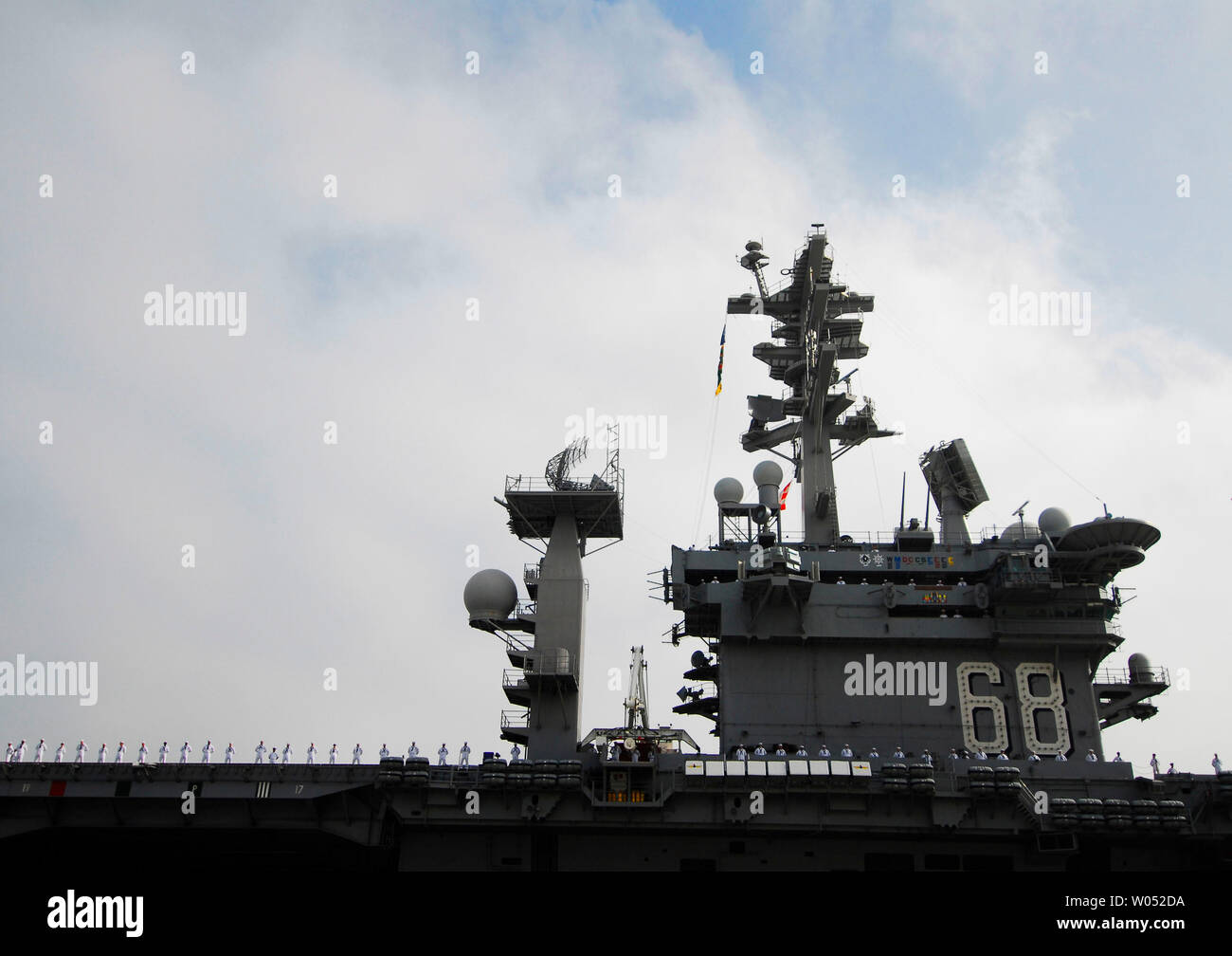 Crewmembers of the aircraft carrier USS Nimitz line the deck as the ...