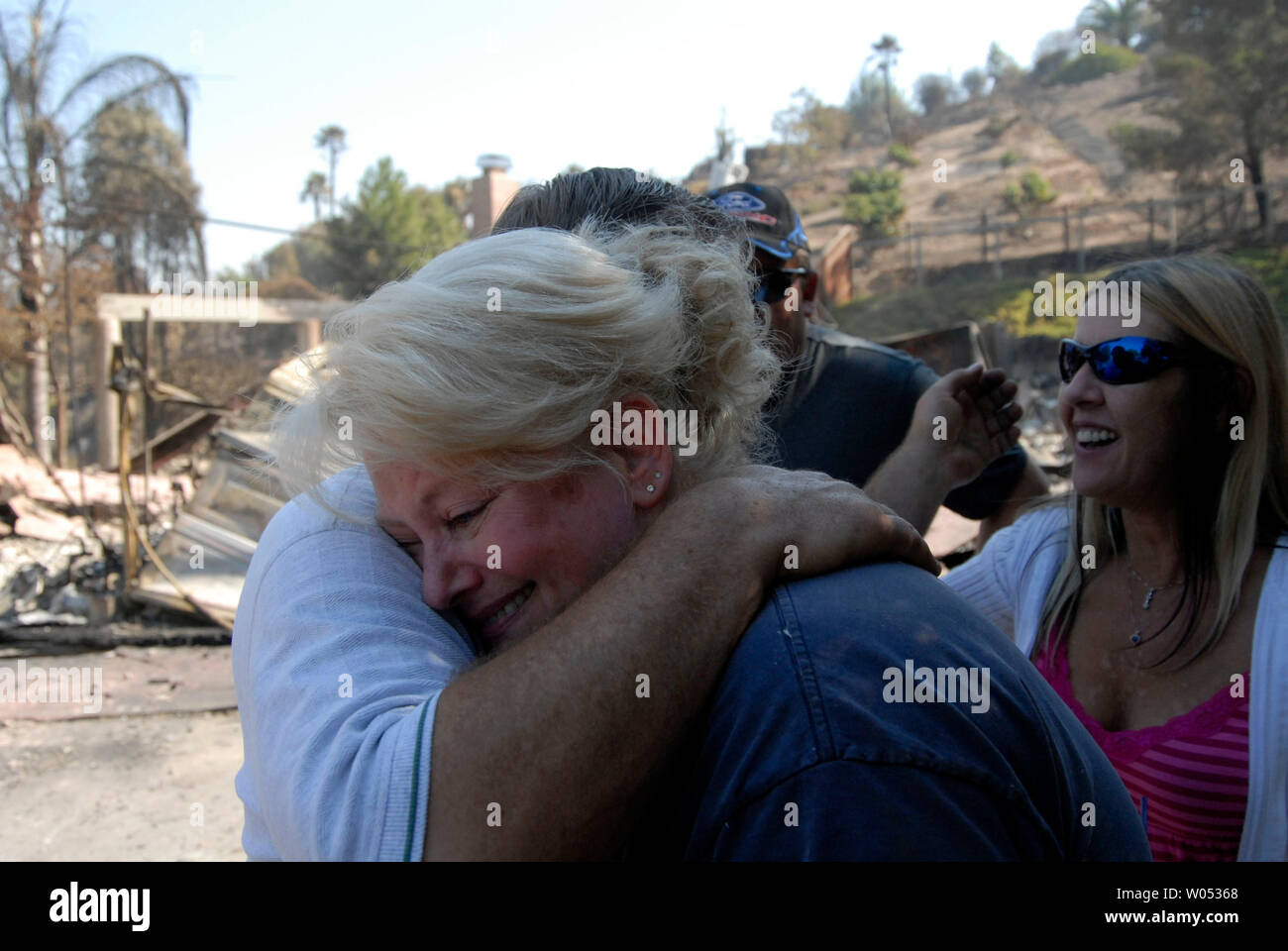 Gary and Jeannette Lyons embrace as Donna and Don Whittaker looks on after finding a small framed photo of their son in their burned out home after the fire that swept through the San Diego neighborhood of Rancho Bernardo, on October 26, 2007. Residents have begun the clean up as firefighters still battle two major fires in the north and eastern parts of the county.  (UPI Photo/Earl Cryer). Stock Photo