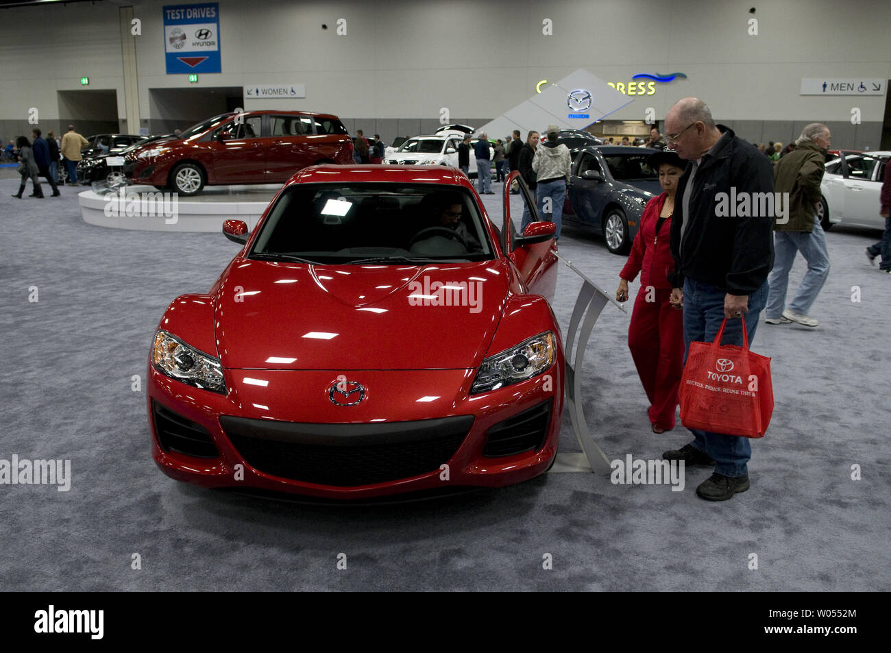 Visitors to the San Diego International Car Show look over a new 2011Mazda RX8, along with some of the over 400 2011 model vehicles on display at the San Diego Convention Center, December 30, 2010 .The auto show is expected to attract over three hundred thousand people and is the six largest in the country, showcasing concept cars and new releases from the top automakers. ( UPI Photo/Earl S. Cryer) Stock Photo