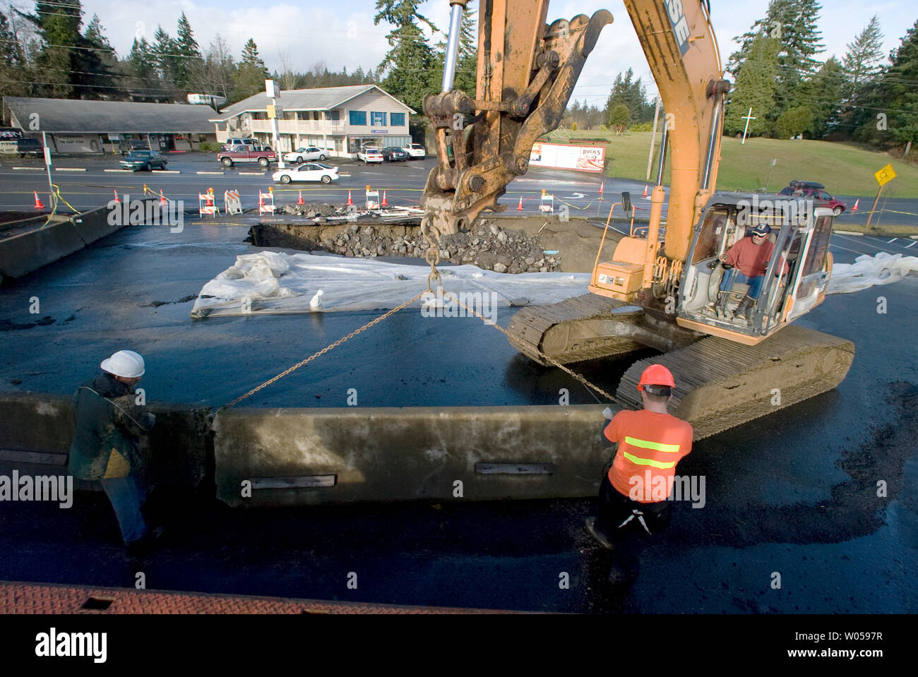 Workers move a barrier into place along a 20-foot-deep sinkhole that opened  up Monday afternoon in the parking lot of the Hi-Joy Bowl in Port Orchard ,  WA., on December 4, 2007.
