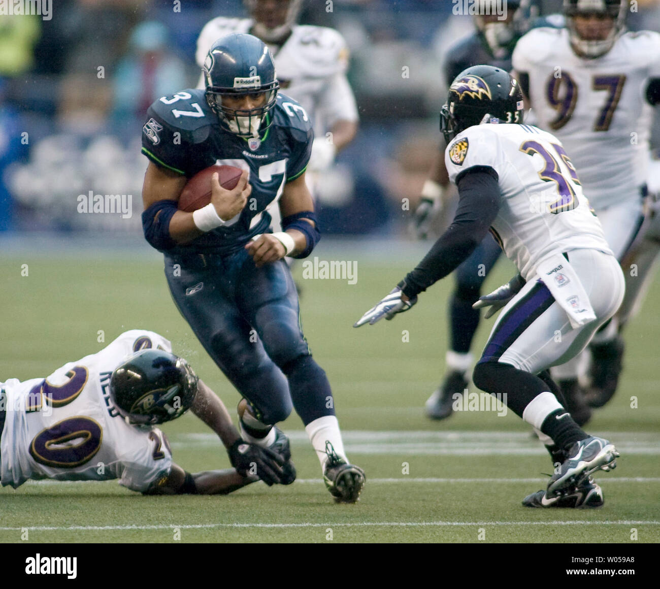 Seattle Seahawks' running back Shaun Alexander (C) runs through the attempted tackles of Baltimore Ravens' free safety Ed Reed (L) and cornerback Corey Ivy (R) enroute to scoring on a 14-yard screen pass from Matt Hasselbeck in the first half at Qwest Field in Seattle on December 23, 2007. Alexander turned a season of being booed at home into holiday cheers by gaining 73 yards on 13 carries and scoring his 100th career touchdown in the Seahawks 27-6 win over the Ravens. (UPI Photo/Jim Bryant). Stock Photo