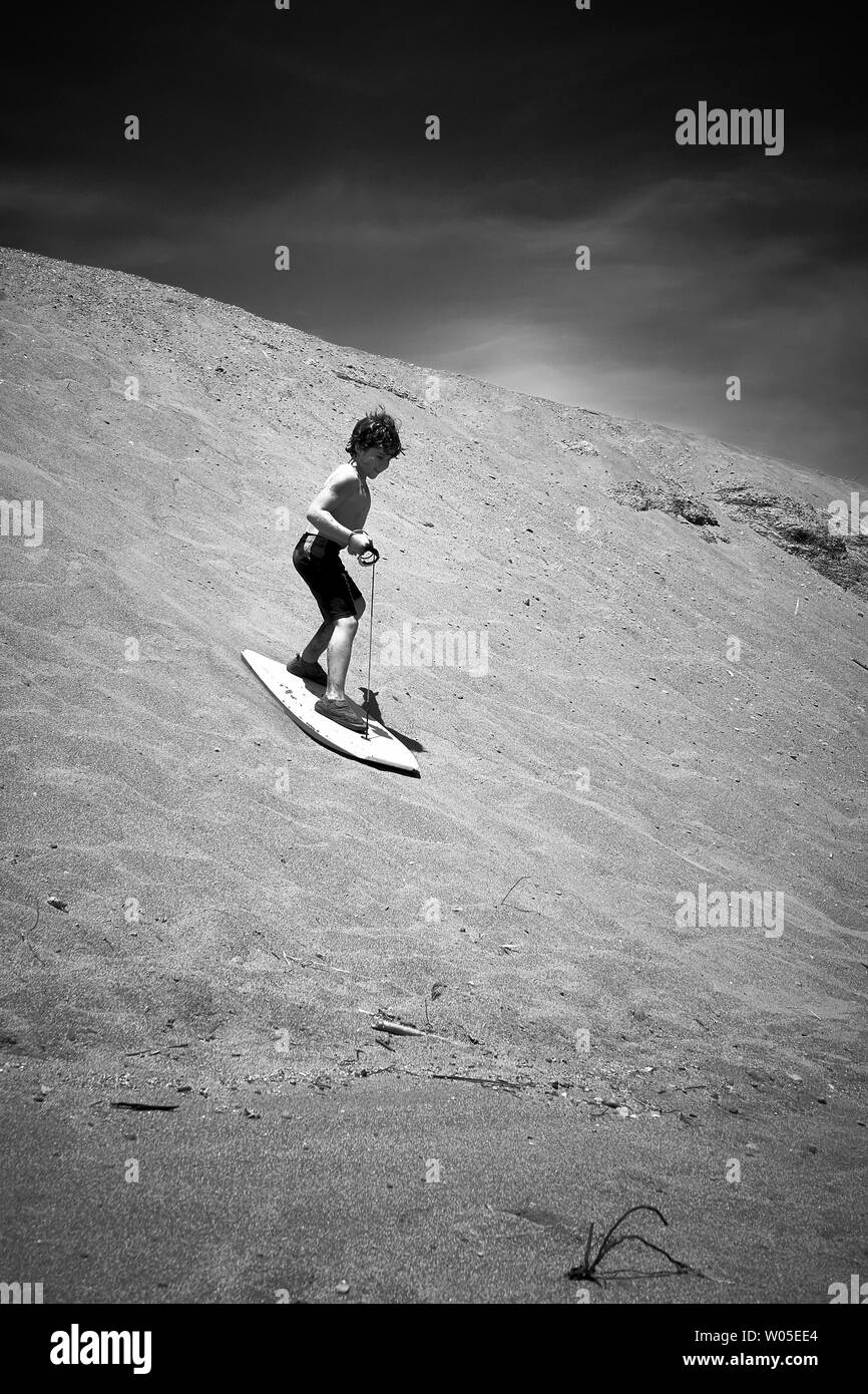 One boy sand surfing on a sand dune at the Pacific Coast and the