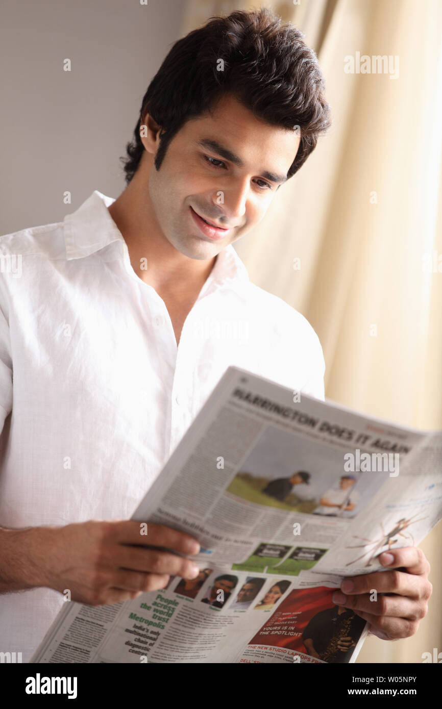 Indian young man reading a newspaper Stock Photo - Alamy