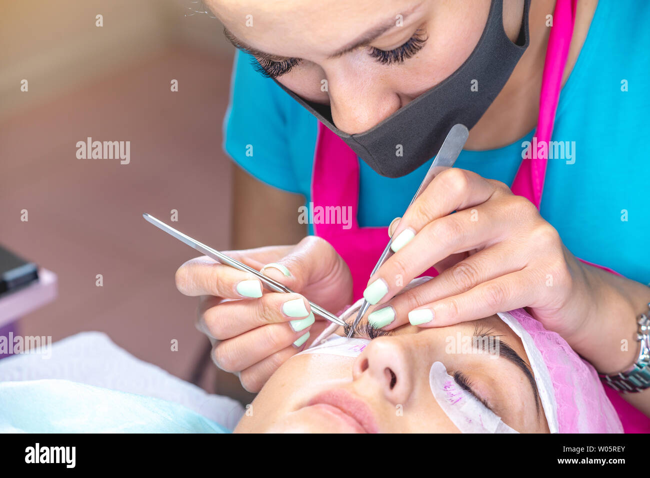 Woman master in the beauty salon work on eyelash extension to the client. Concept of profession in the field of beauty services Stock Photo
