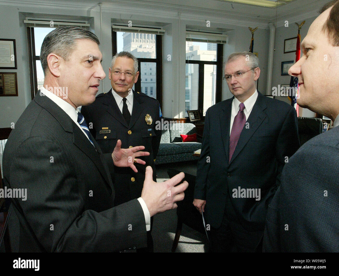 Frank Libutti, Under Secretary for Information Analysis and Infrastructure Protection for U.S. Department of Homeland Security (L)  talks to (L to R) St. Louis Police Chief Joe Mokwa, Mo Gov. Bob Holden and St. Louis Mayor Francis G. Slay before presenting St. Louis with a computer-based counterterrrorism communications system at Police Headquarters in St. Louis on February 27, 2004. This communications capability will deliver to states and major urban areas real-time interactive connectivity with the DHS Homeland Security Operations Center through the Joint Regional Informaton Exchange System Stock Photo