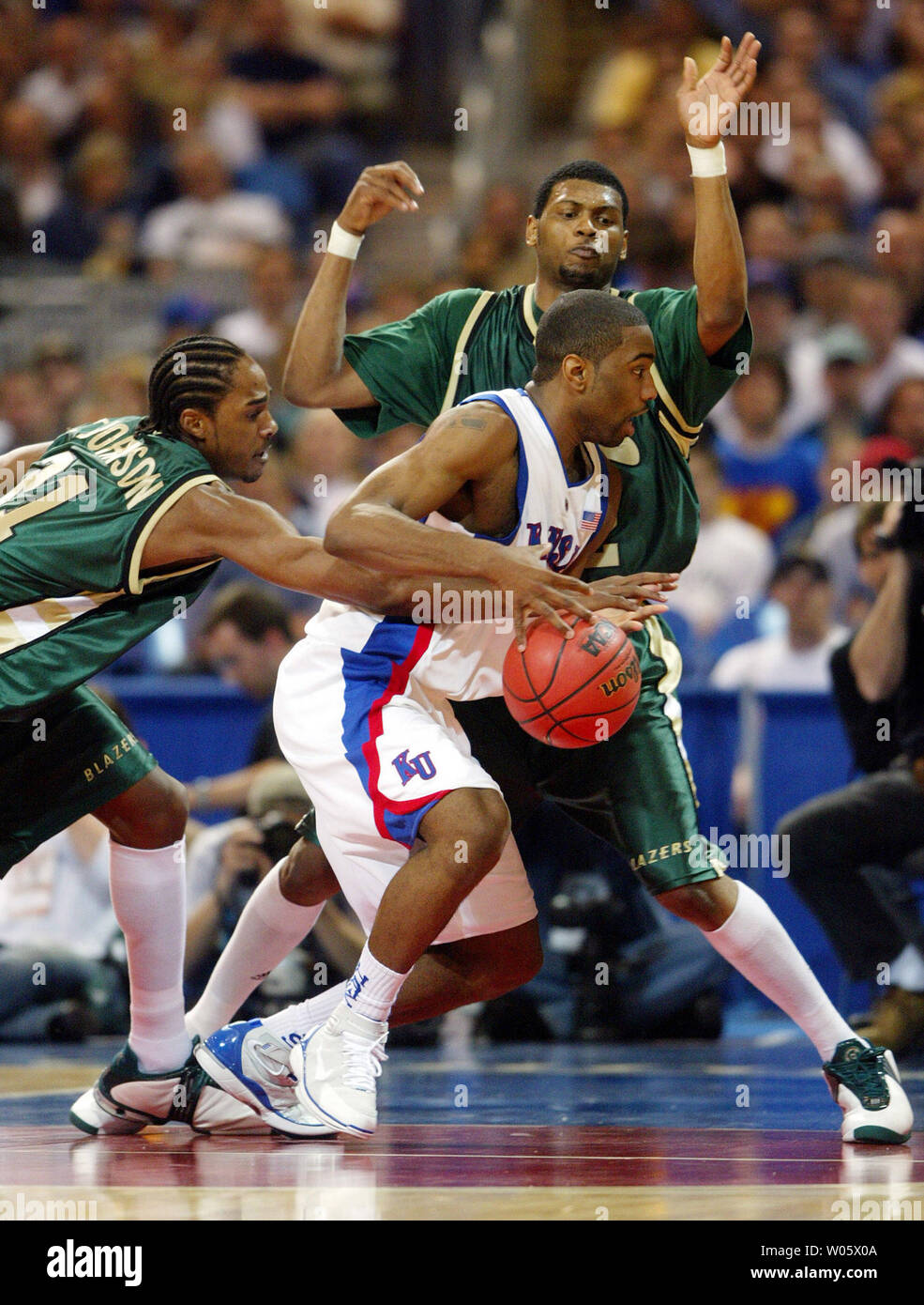 Alabama- Birmingham's Tony Johnson (L) gets a hand on the basketball, knocking it away from Kansas' Kieth Langford as UAB's Sidney Ball defends during their NCAA Regional game at the Edward Jones Dome in St. Louis on March 26, 2004.   (UPI Photo/Bill Greenblatt) Stock Photo