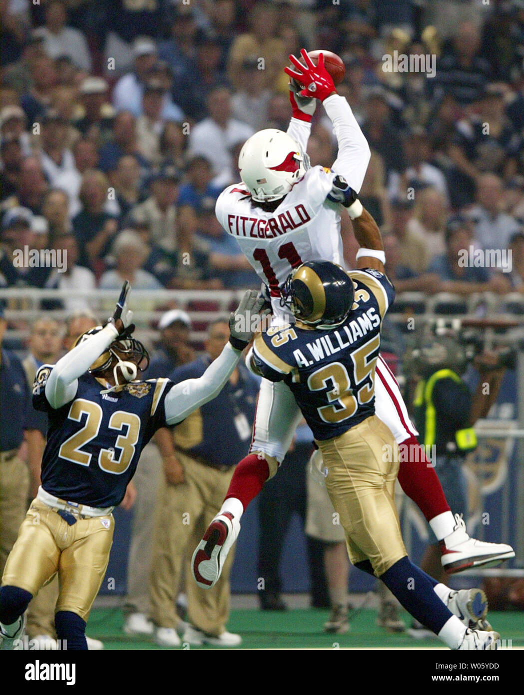 Arizona Cardinals Larry Fitzgerald jumps to catch the football for a 37-yard gain in front of St. Louis Rams Aeneas Williams (35) and Jerametius Butler (23)  for the first play of the game at the Edward Jones Dome in St. Louis on September 12, 2004. (UPI Photo/Bill Greenblatt) Stock Photo