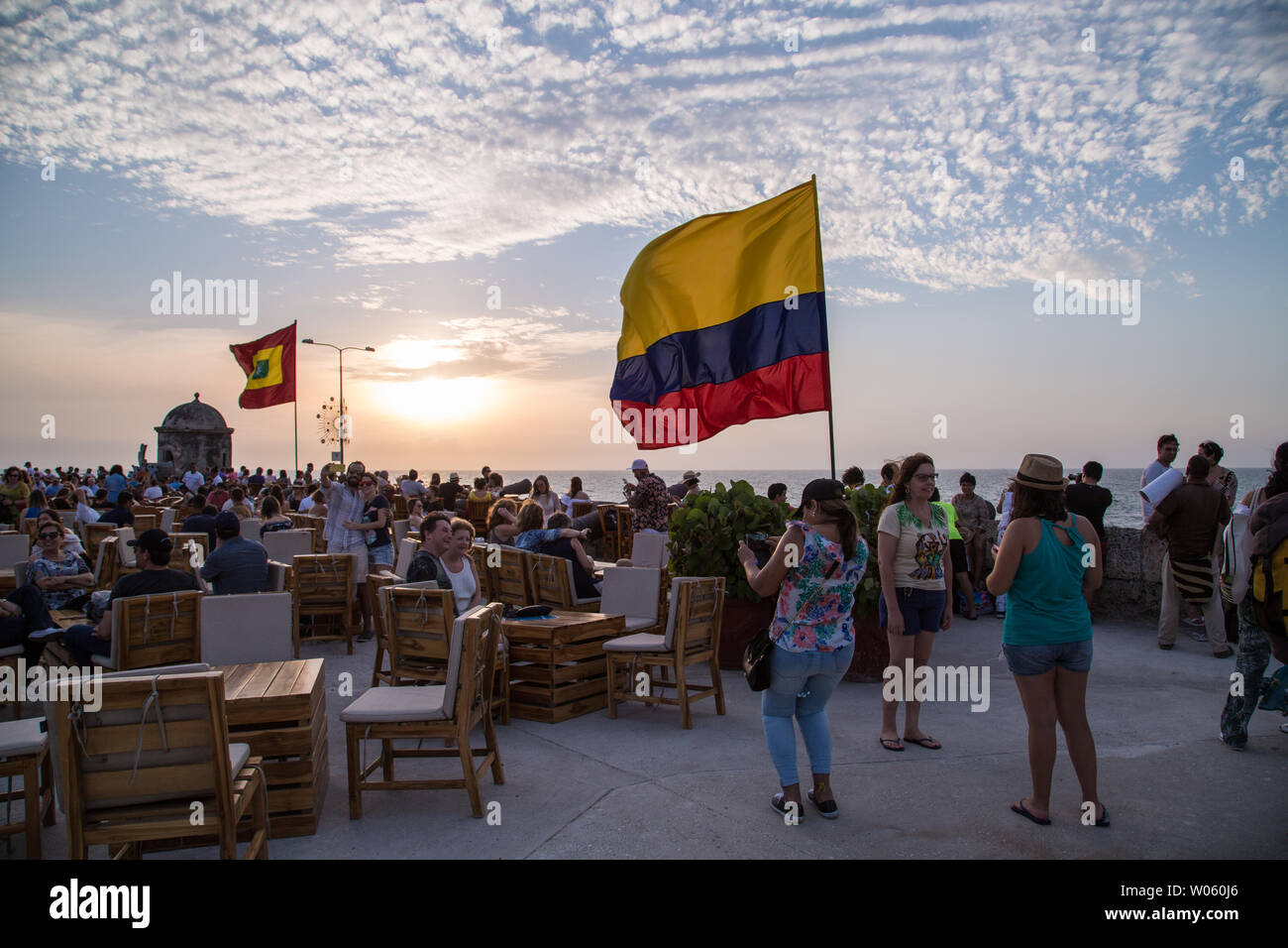A sunset in Cartagena, Colombia, with the Colombian flag flying in the foreground, at the famous Cafe Del Mar, a tourist spot. Stock Photo