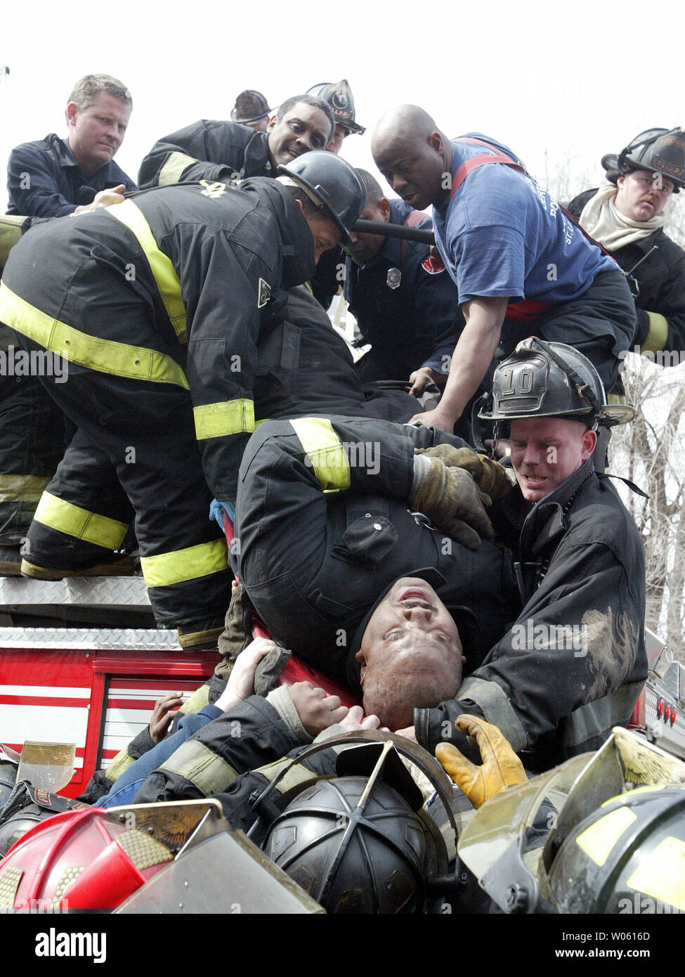 St. Louis firefighters lower fellow firrefighter Leonard Davis down to a waiting ambulance after Davis tumbled backwards down a hook and ladder during a two-alarm fire in north St. Louis on March 21, 2005. Moments earlier, firefighters discovered the body of a woman in a burned-out bedroom at the two-story home . Davis was taken to a local hospital for treatment of a possible broken foot. (UPI Photo/Bill Greenblatt) Stock Photo