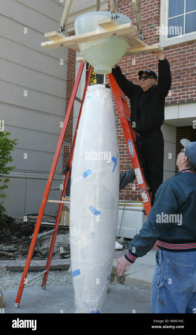 With the help of a worker, artist Howard Ben Tre' lowers the top of the 'Clayton Carytid' into place in Clayton, MO on May 3, 2005. The ten-foot-tall, 1,600 pound sculpture is formed in the shape of a draped female figure, adorned in low expansion glass, painted bronze and polished granite. (UPI Photo/Bill Greenblatt) Stock Photo