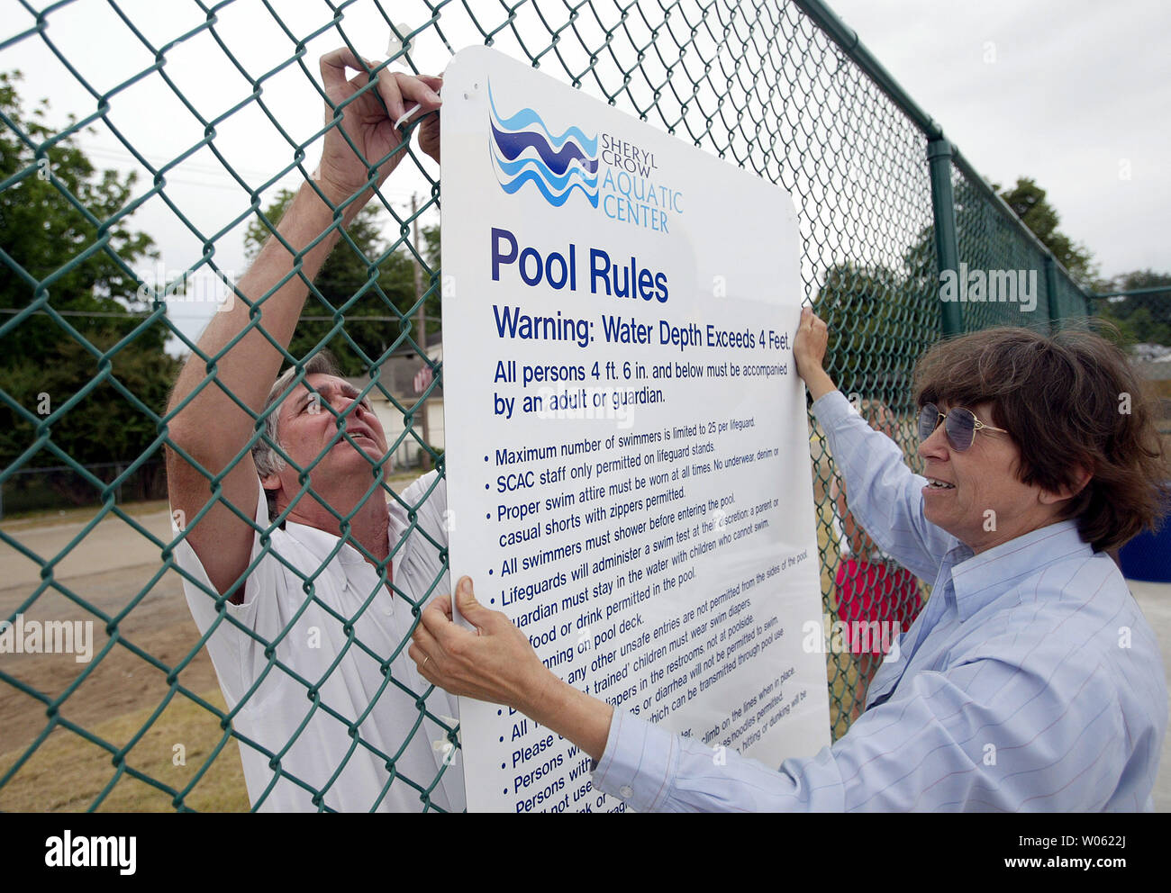 Deborah Milburn (R) helps husband Doug as he attaches a sign at the new