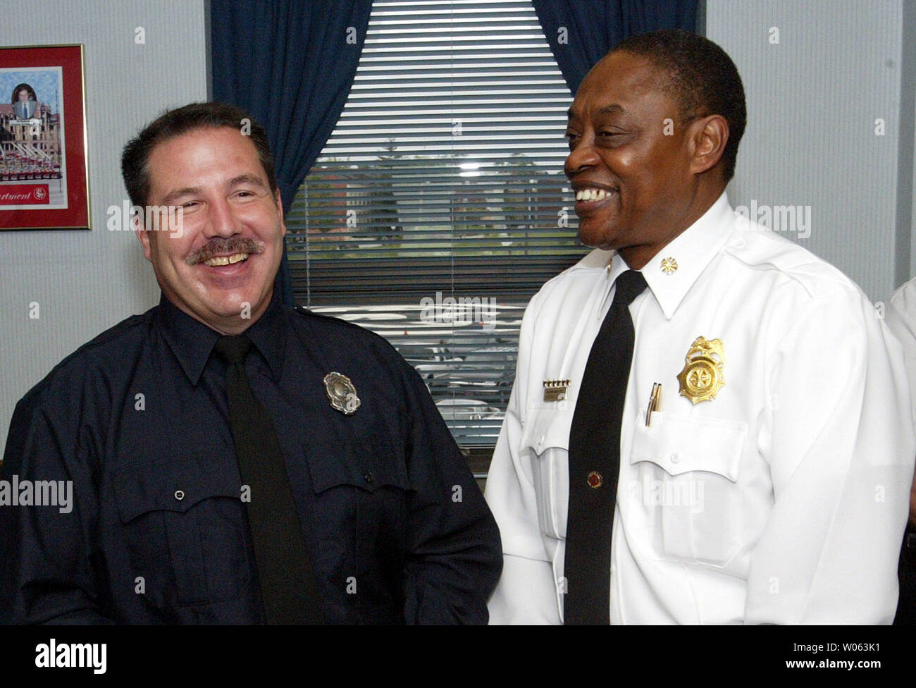 St. Louis firefighter John Heranadez (L) Is all smiles after Fire Chief Sherman George informs him that he has been awarded the Liberty Mutual National Firemark Award for Heroism in St. Louis on October 31, 2005. Hernandez of Engine Company 32 on the cities south side, is being honored for saving a three-year-old boy in a house fire in October 2004. Hernandez's nomination competed nationally with 25 other local award winners and was selected as the national award winner last month. The award, which will be officially given on November 4 at Walt Disney World in Florida, also comes with a $10 th Stock Photo
