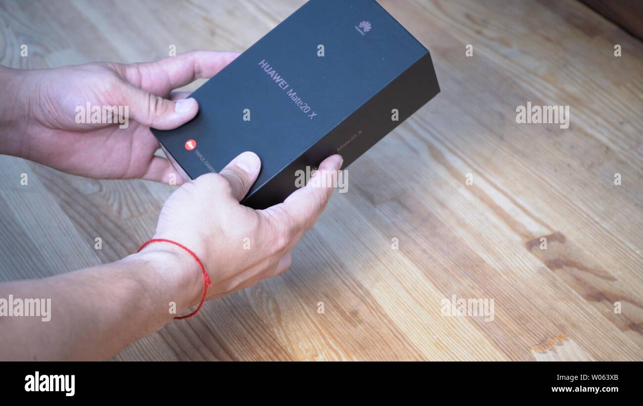 Mans hands holding black box with telephone inside on wooden background. He is showing logo of the company printed on the luxury package Kyiv, Ukraine Stock Photo