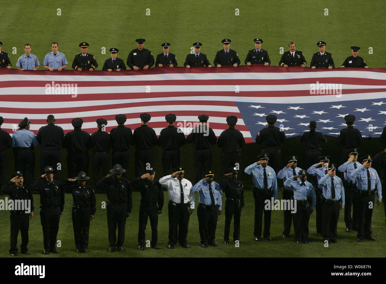 St. Louis area firefighters, police and rescue personel hold an oversized American flag during a moment of silence for the five-year anniversary of 911 attacks of 2001 in New York, Washington and Pennsylvania before the Houston Astros-St. Louis Cardinals game at Busch Stadium in St. Louis on September 11, 2006. (UPI Photo/Bill Greenblatt) Stock Photo