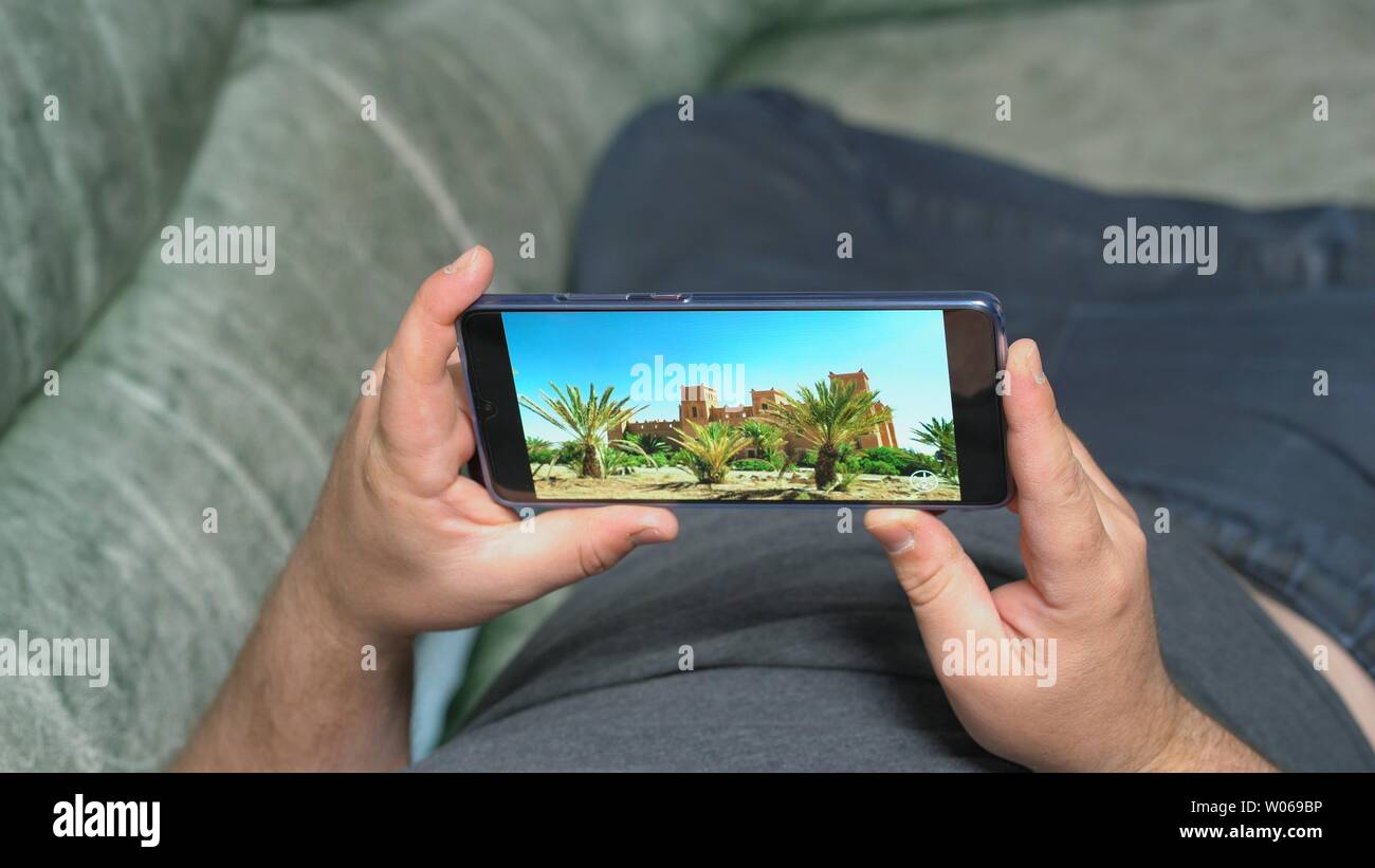 Man lying on couch and watching video about nature and arabian architecture  in high definition through Huawei Mate 20 X smartphone. Display shows extr  Stock Photo - Alamy