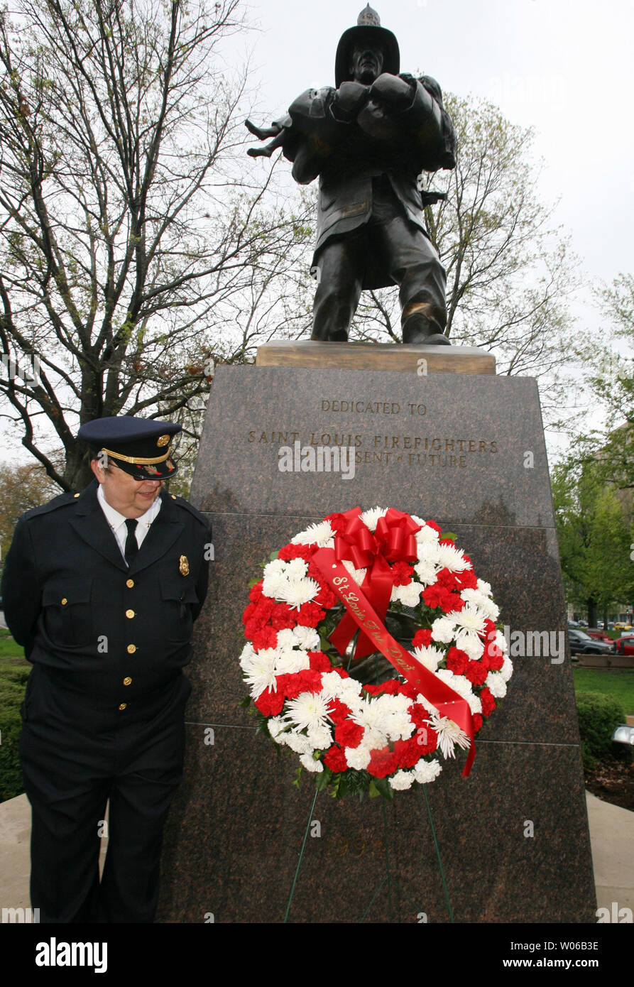 St. Louis Battalion Chief Chris Cross inspects flowers placed at the foot of the firefighters memorial statue in St. Louis on May 3, 2007. A service was held to remember St. Louis firefighters Derek Martin and Rob Morrison who lost their lives in a fire, on this date in 2002. The memorial service included the reading of all 165 St. Louis firefighters names who have died in the line of service for the last 150 years. (UPI Photo/Bill Greenblatt) Stock Photo