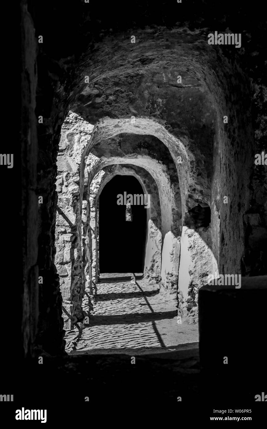 Ancient dark stone passage way with sunlight shining in to the shadows at Castle Rising in Norfolk Stock Photo