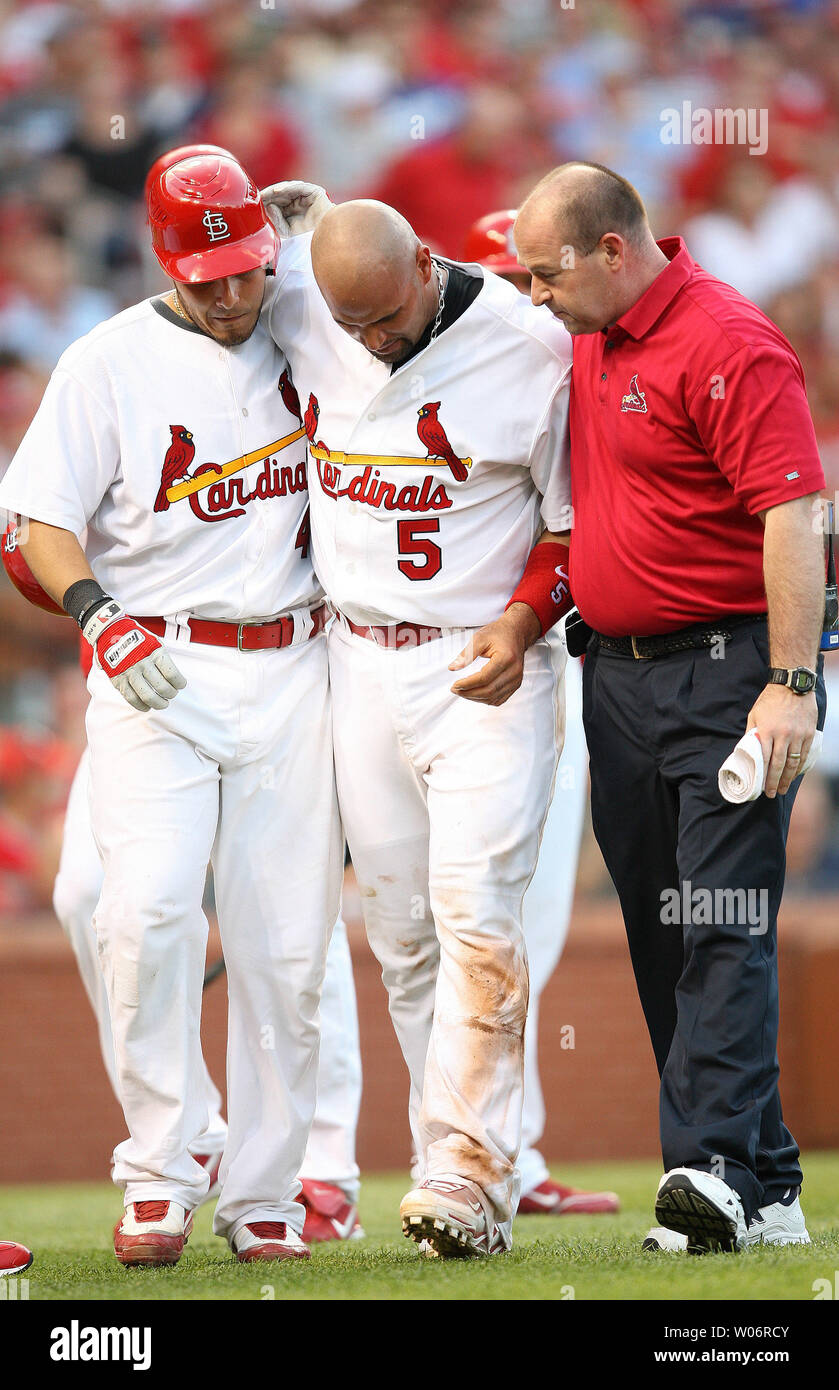 St. Louis Cardinals Albert Pujols (5) is helped off the field by teammate  Yadier Molina (L) and assistant trainer Brad Hauck after being hit in the  head by a baseball as he