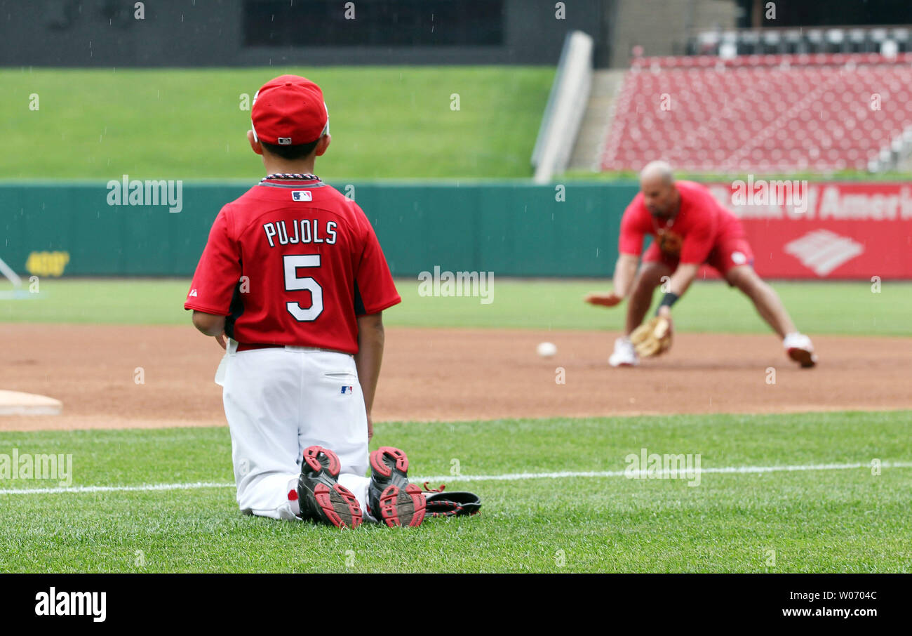 Albert Pujols Jr. (10) kneels while watching his dad St. Louis Cardinals Albert  Pujols take fielding practice at first base before a game against the  Arizona Diamondbacks at Busch Stadium in St.