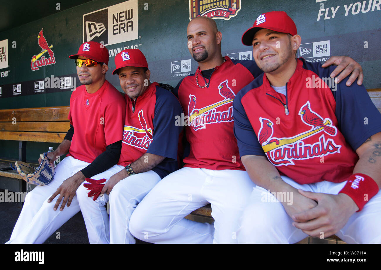 St. Louis Cardinals players (R to L) Yadier Molina, Albert Pujols and  Rafael Furcal (L) pose for a photograph in the dugout with Domician singer  Hector Acosta before a game against the
