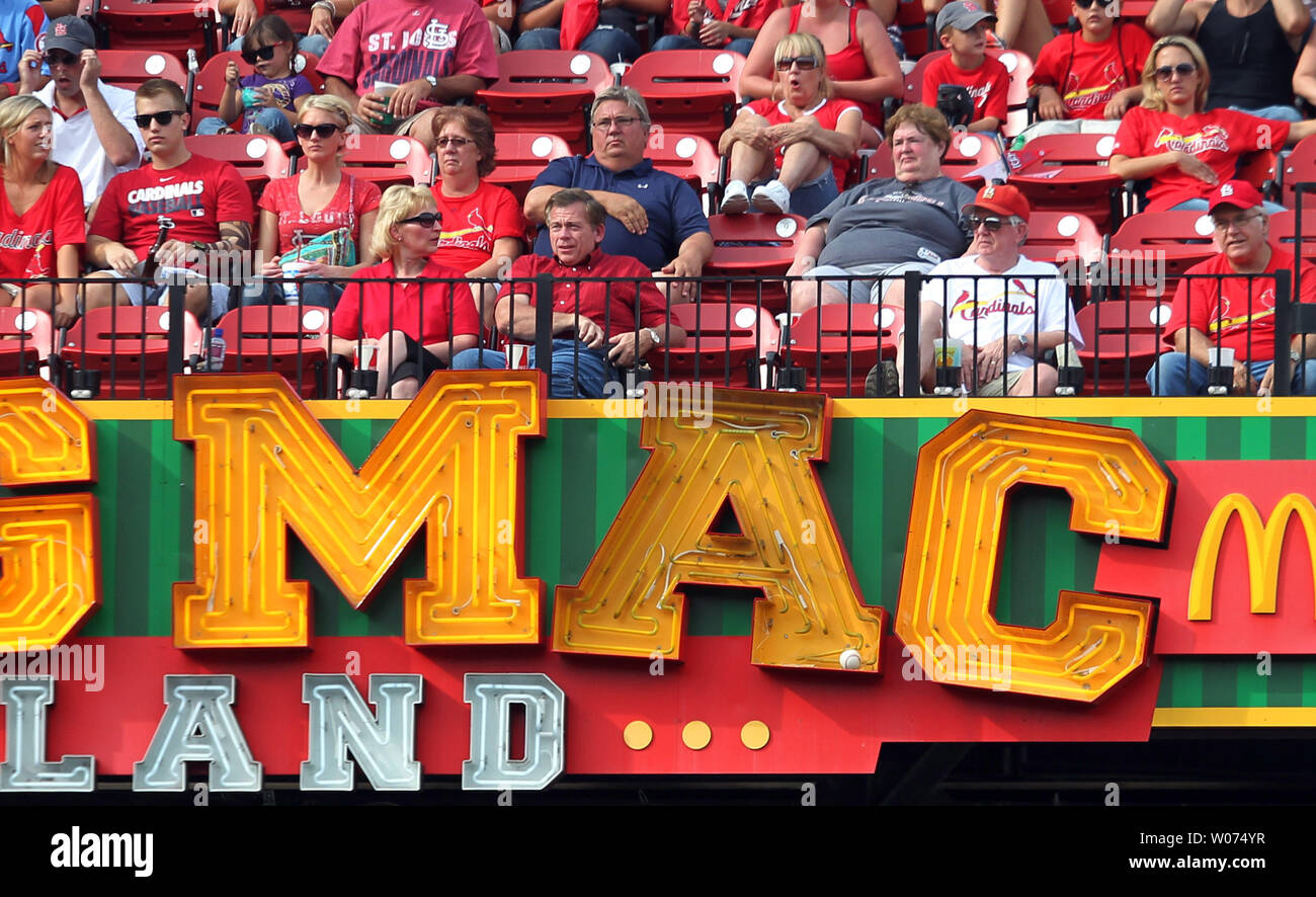 Fans in Big Mac Land enjoy a baseball game between the Pittsburgh Pirates  and the St. Louis Cardinals at Busch Stadium while a baseball remains  lodged in the A of the neon