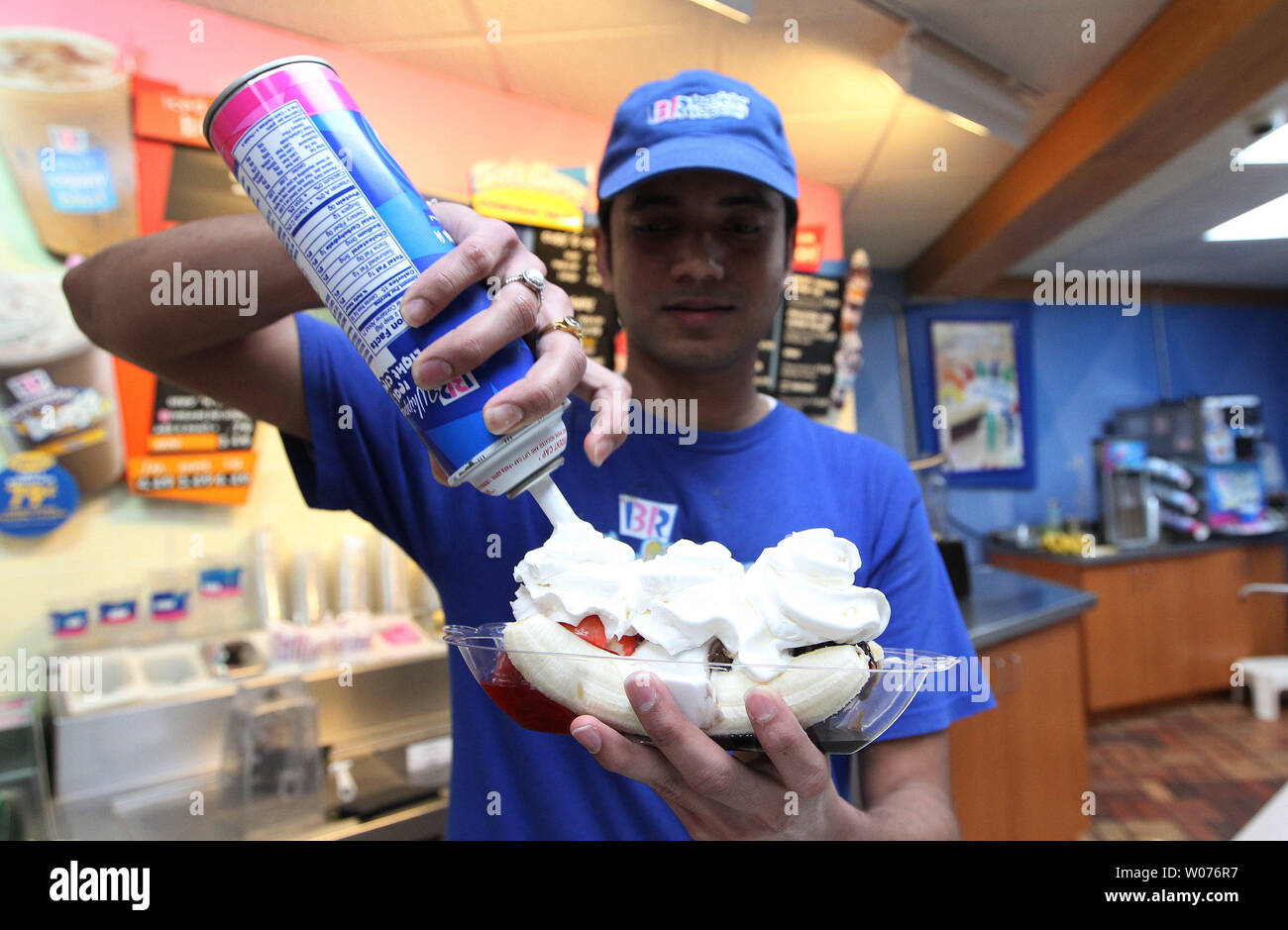 Saumin Patel applies whip cream to a bananna split on National Whipped Cream Day while working at Baskin Robbins in Ladue, Missouri on January 5, 2013. National Whipped Cream Day is celebrated on the birthday of Reddi-wip founder and creator Aaron 'Bunny' Lapin.  Lapin did not invent whipped cream, but he was the first person to put whipped cream in an aerosol spray.  UPI/Bill Greenblatt Stock Photo