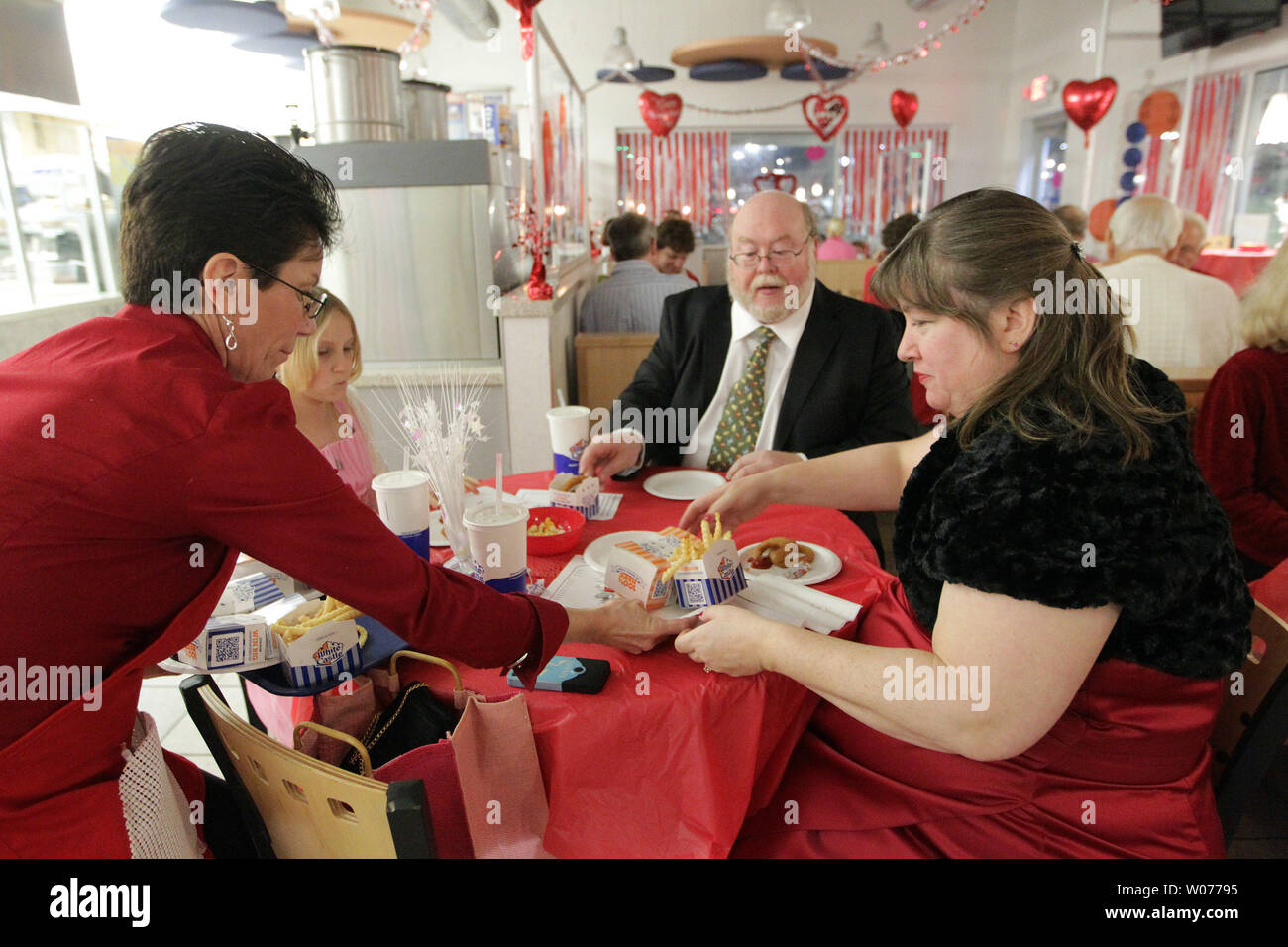 Waitress Nola Rose serves Joe Pinegar, his fiancee Karin Ransden and their daughter Katherin, their burgers and fries while dining at a White Castle restaurant in Kirkwood, Missouri on February 14, 2013. The burger joint, home of the 69 cent slider, converts itself on into a romantic eating establishment with tablecloths, candles and table service for dinner on Valentines Day. UPI/Bill Greenblatt Stock Photo