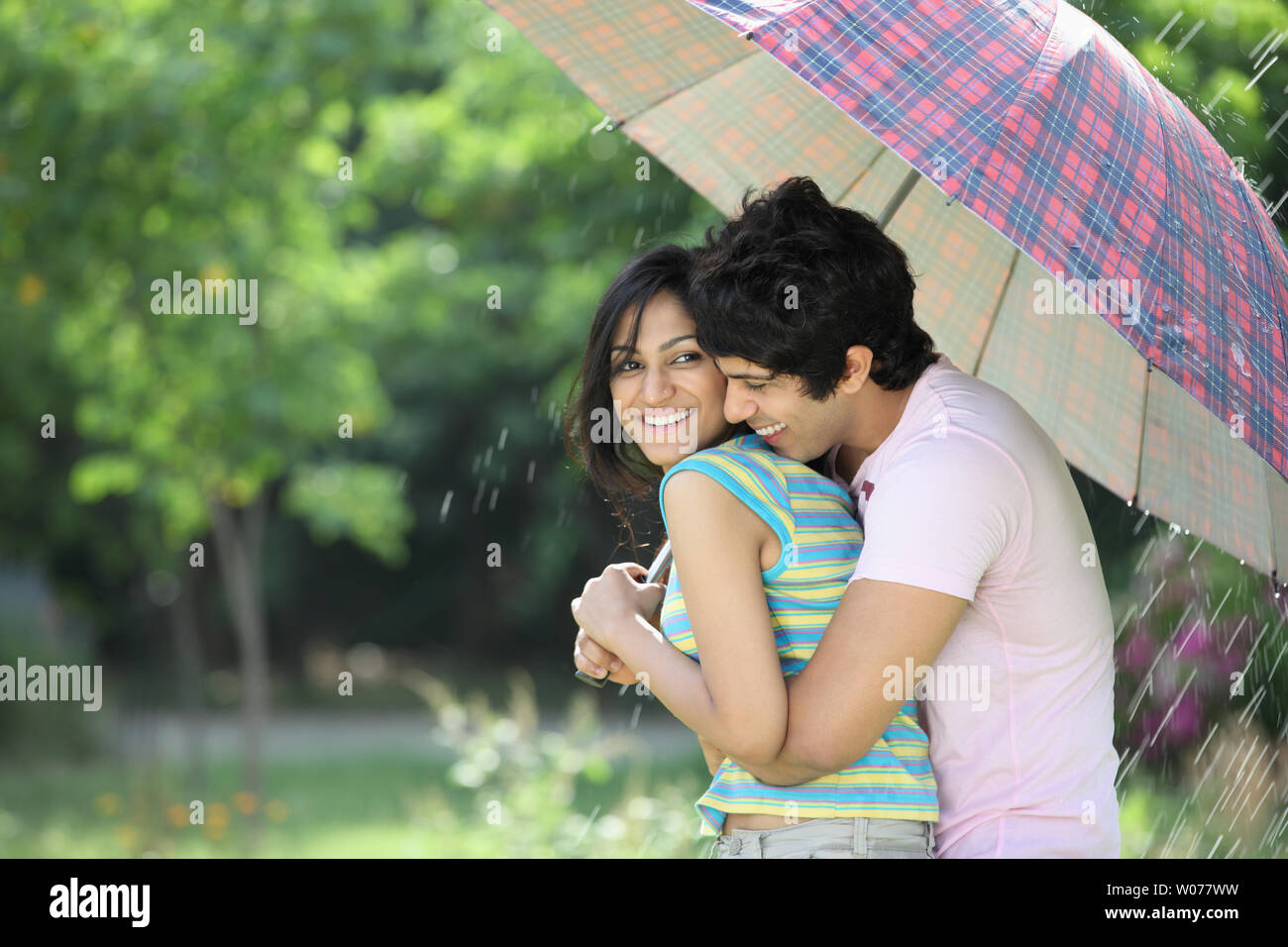 Indian young couple under an umbrella in the rain Stock Photo - Alamy