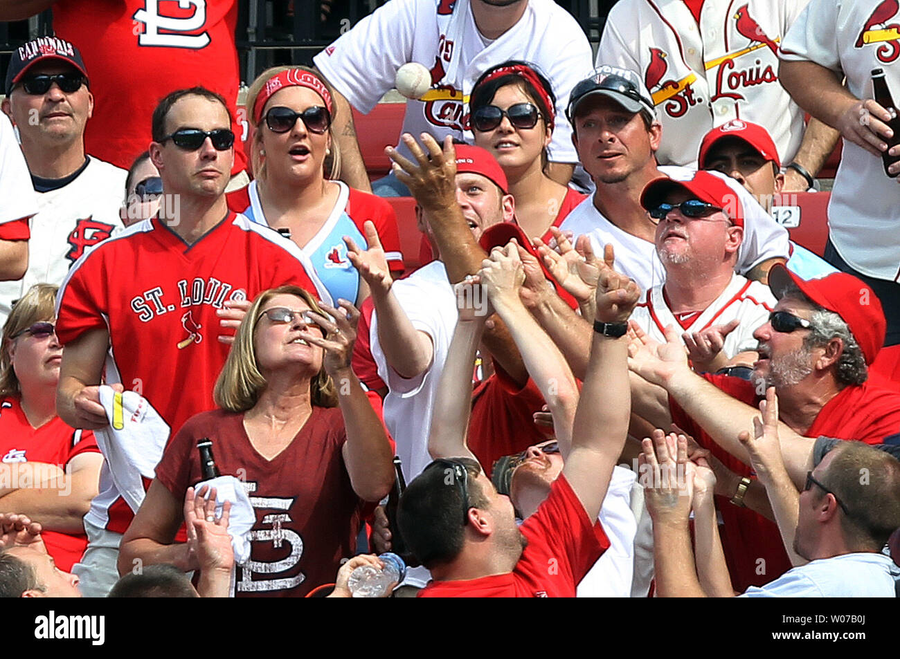 St. Louis Cardinals fans in the center field bleachers reach for a